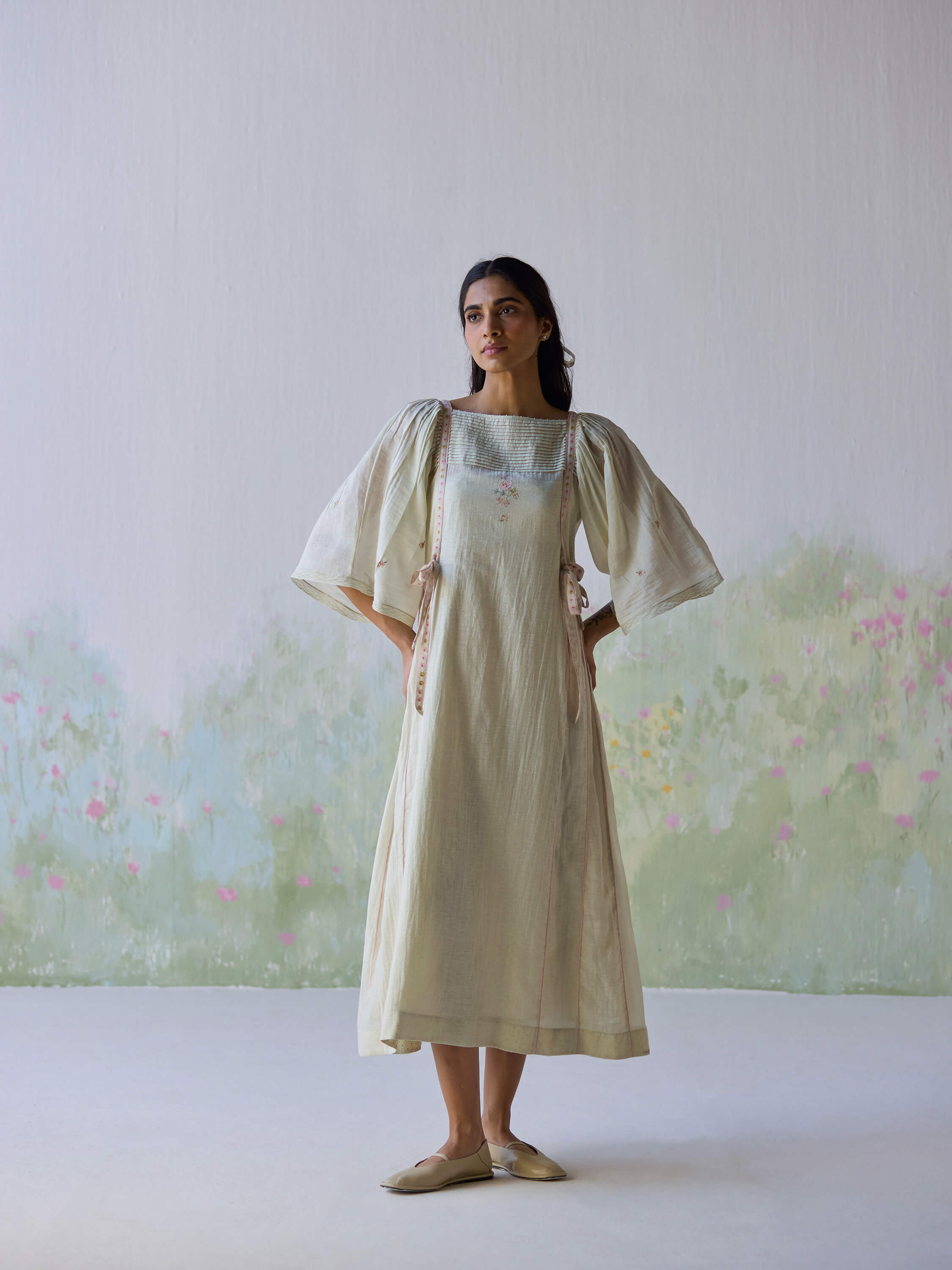 Amore Midi Dress worn by a model against a pastel floral background.