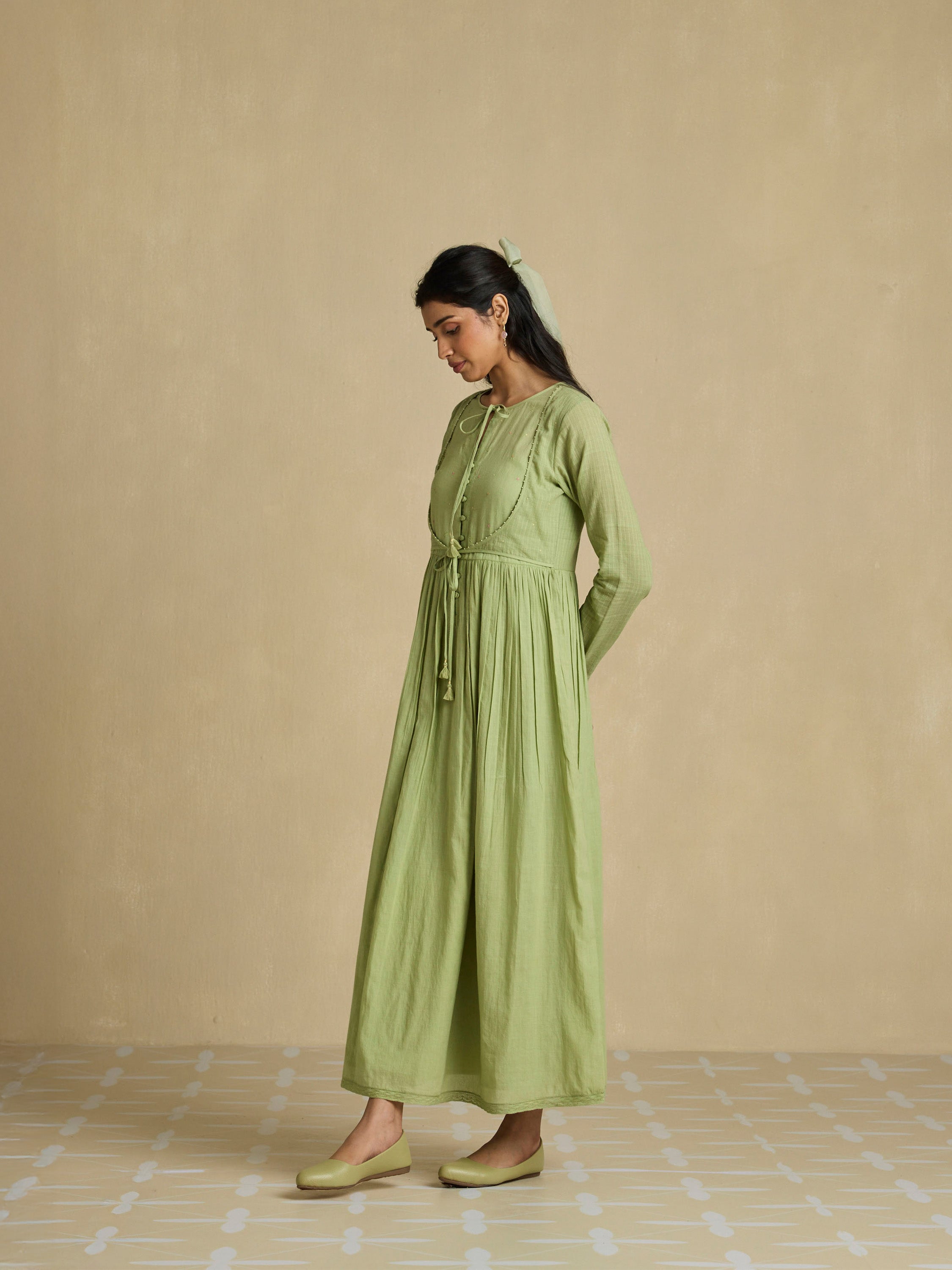 Woman wearing a green dress against a beige background