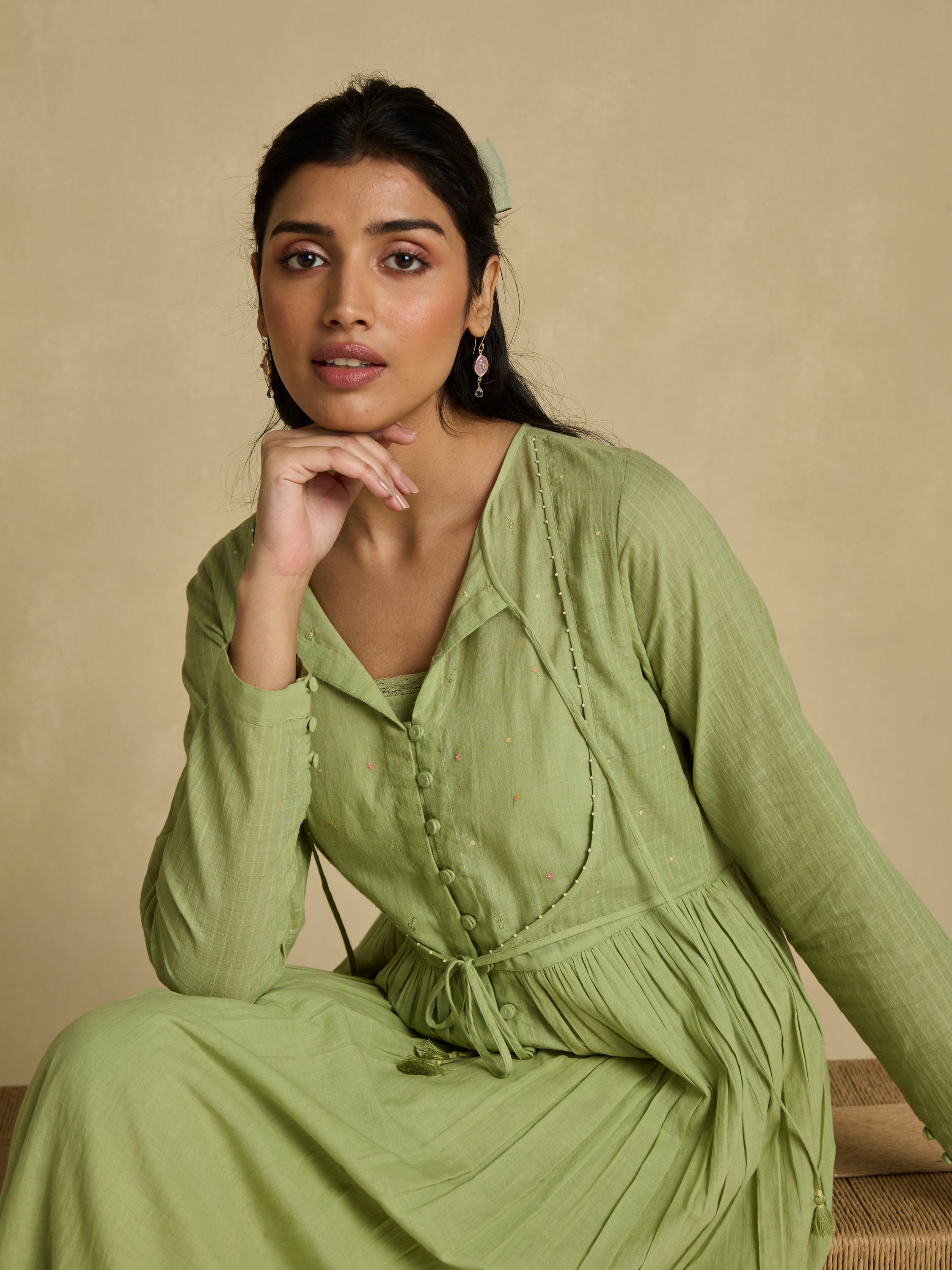 Woman wearing a green dress sitting on a beige background
