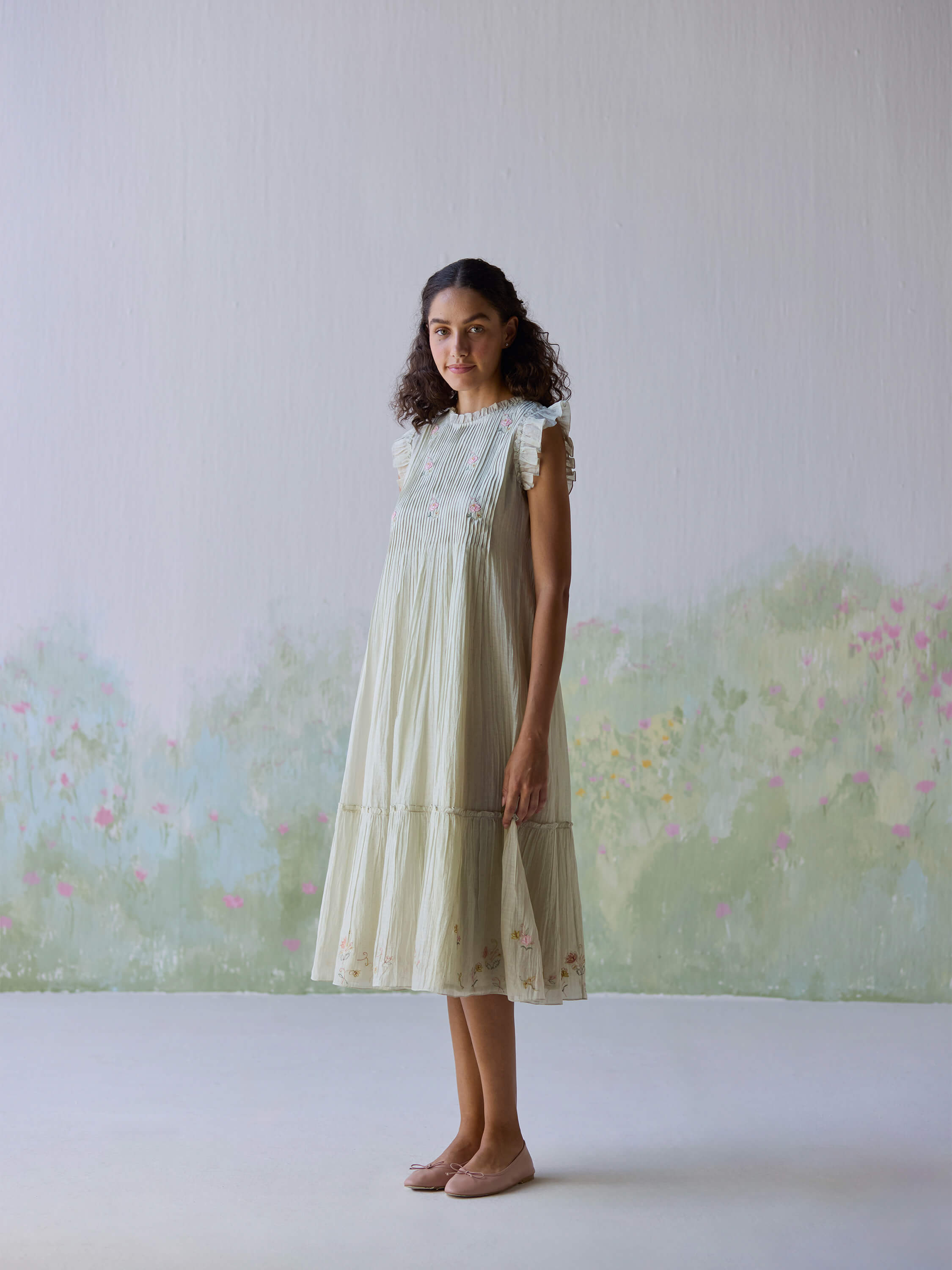 "Flutter Fields Midi Dress on model with floral details and soft pastel background."