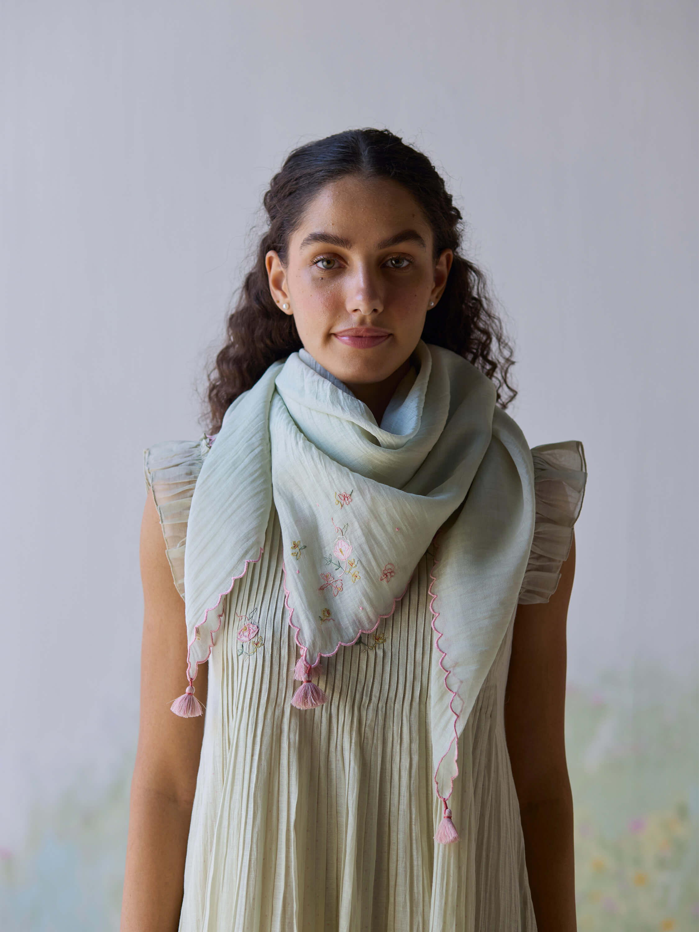 Model wearing Minty Breeze Scarf with floral embroidery and tassels.