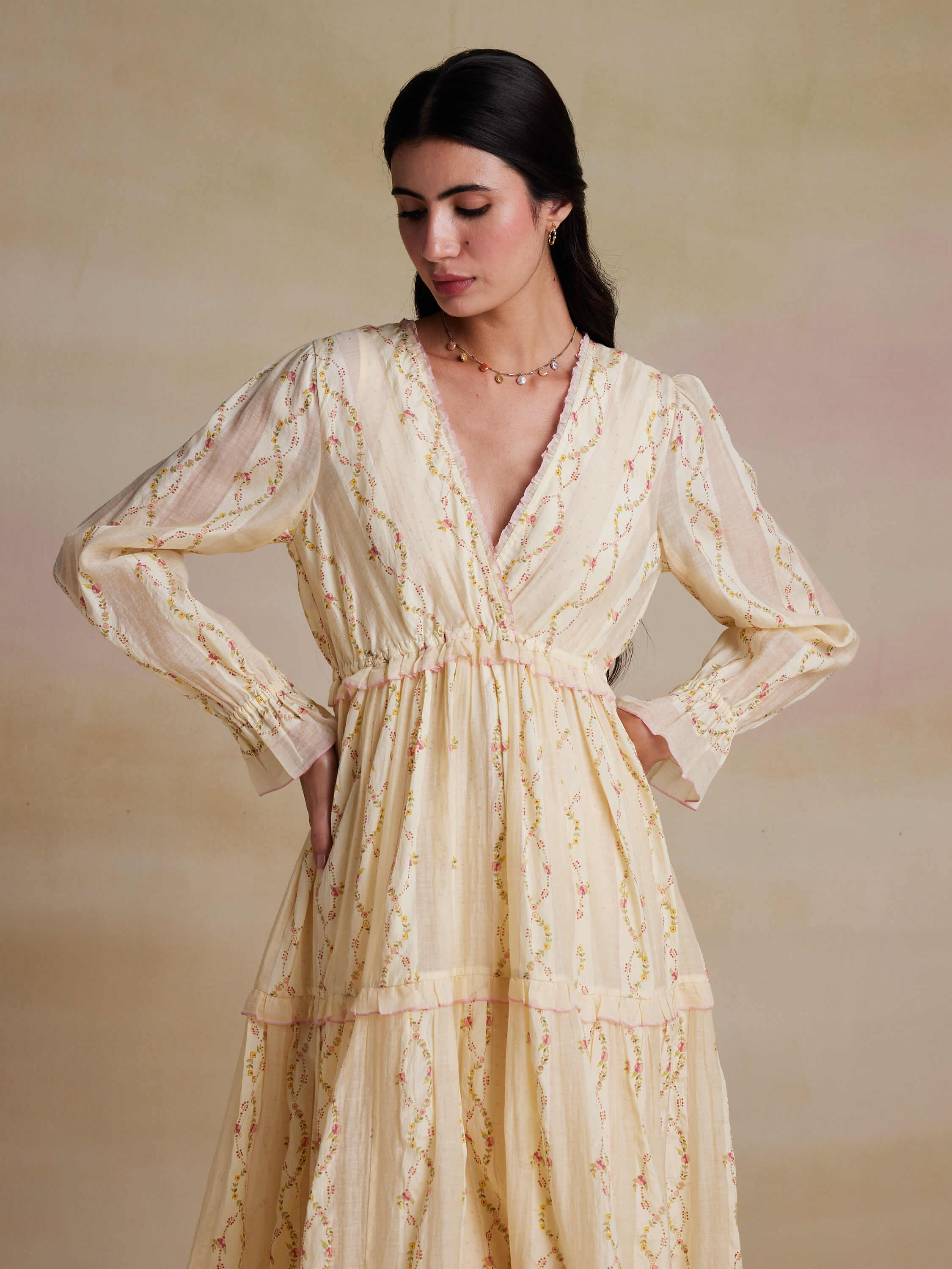 Woman in floral long-sleeve V-neck dress with subtle smile.