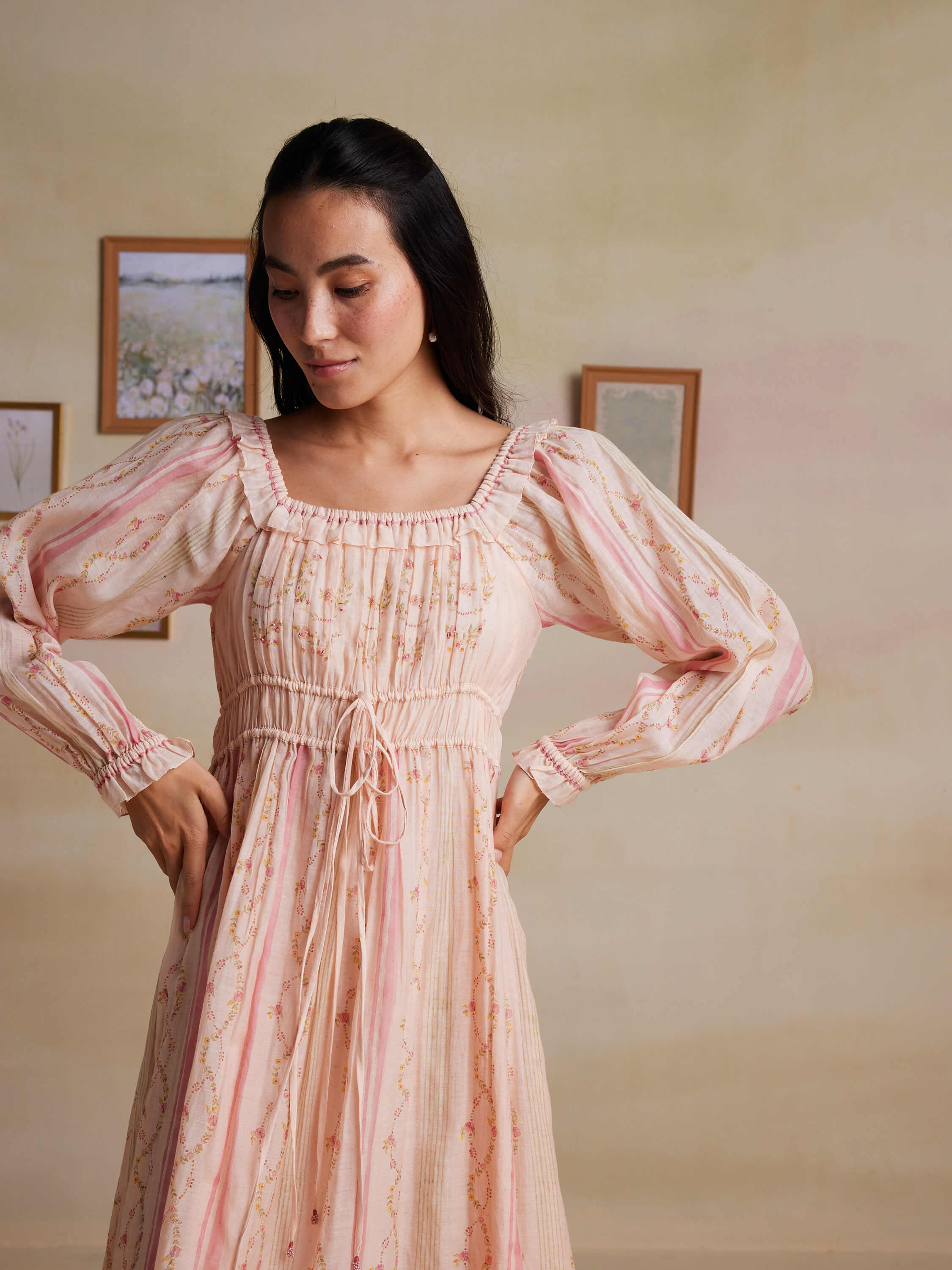 Woman wearing a floral long-sleeve pink dress posing indoors.