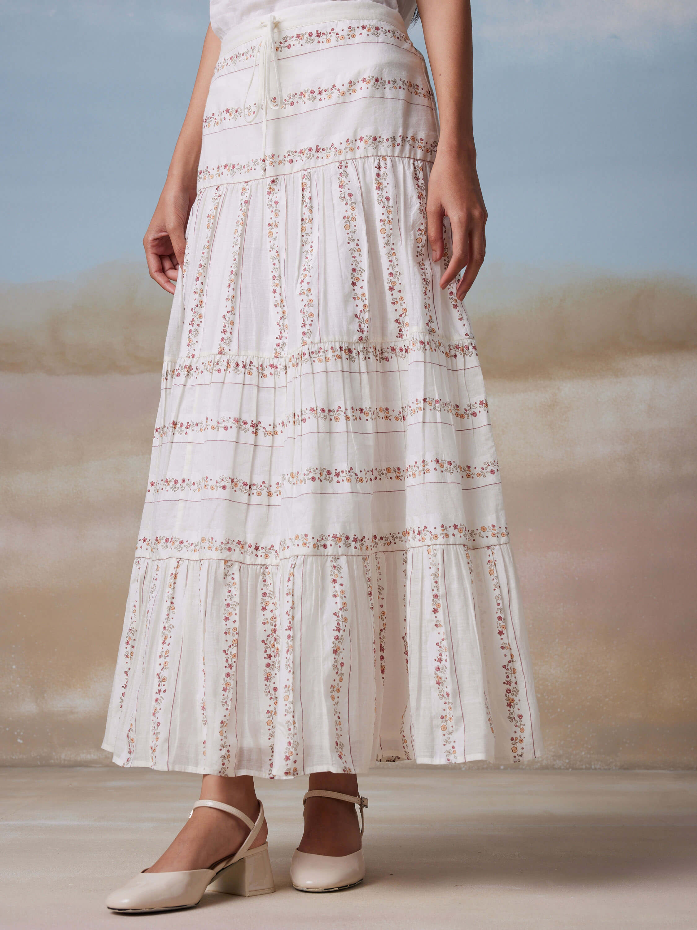 Woman wearing a floral maxi skirt and beige block heel shoes.