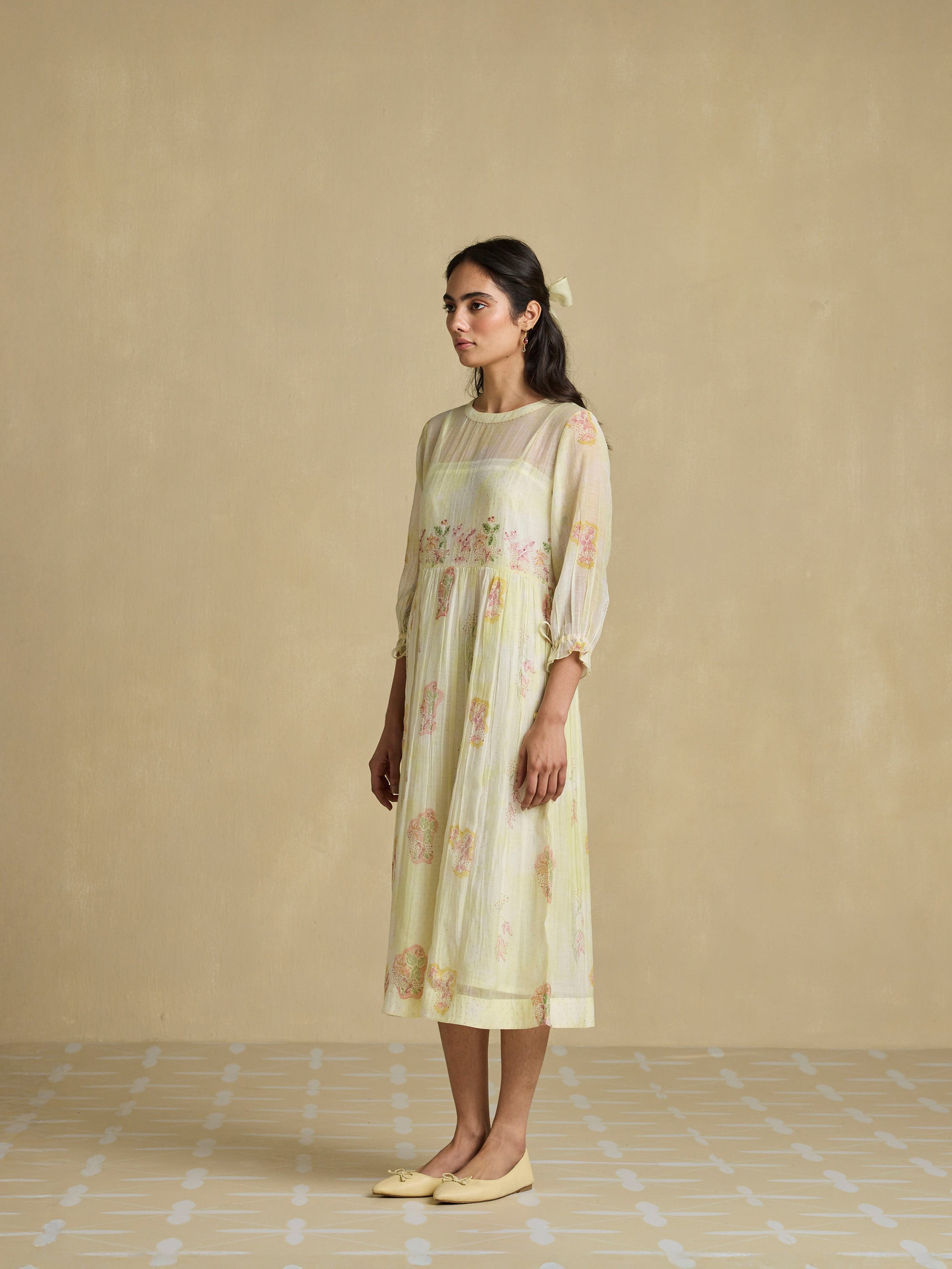 Woman wearing a light-colored dress with floral patterns against a beige background