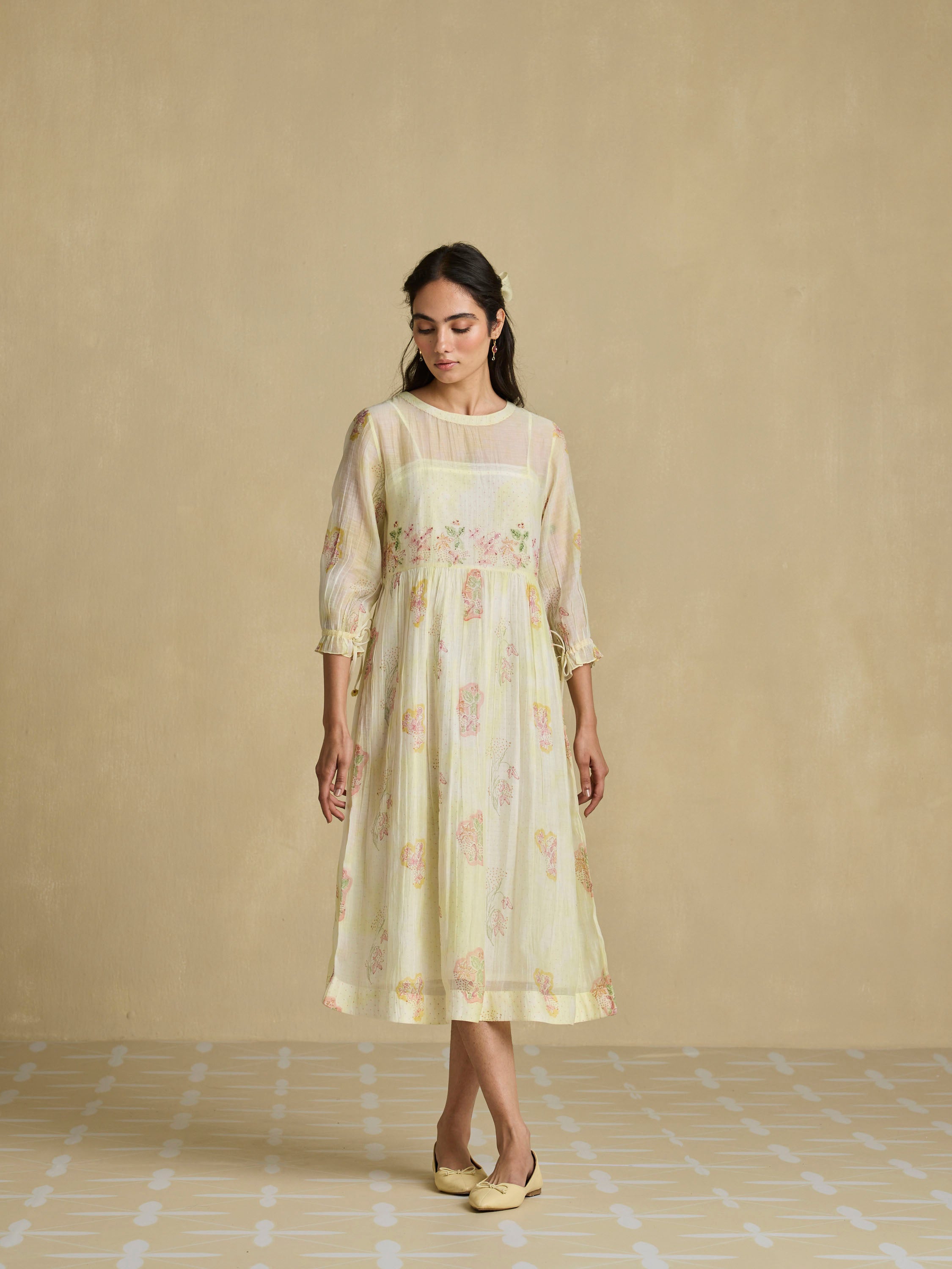 Woman wearing a light-colored dress with floral patterns against a beige background