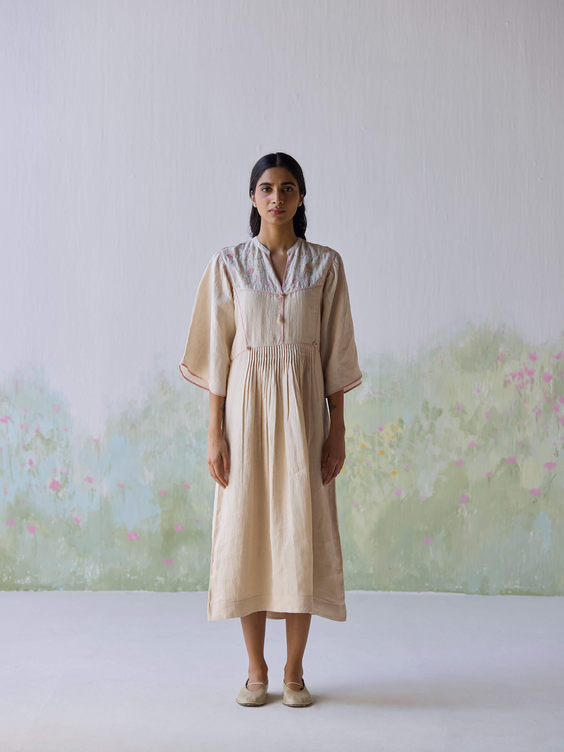 Sweetly embroidered kaftan dress model against a floral background.