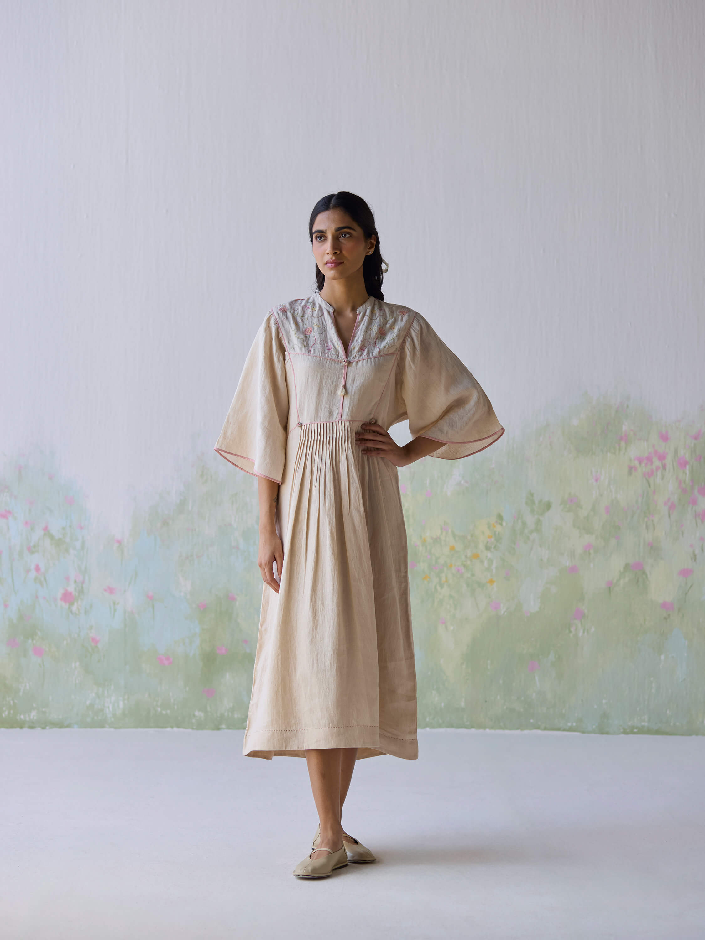Sweetly embroidered kaftan dress on model against a soft, floral background.