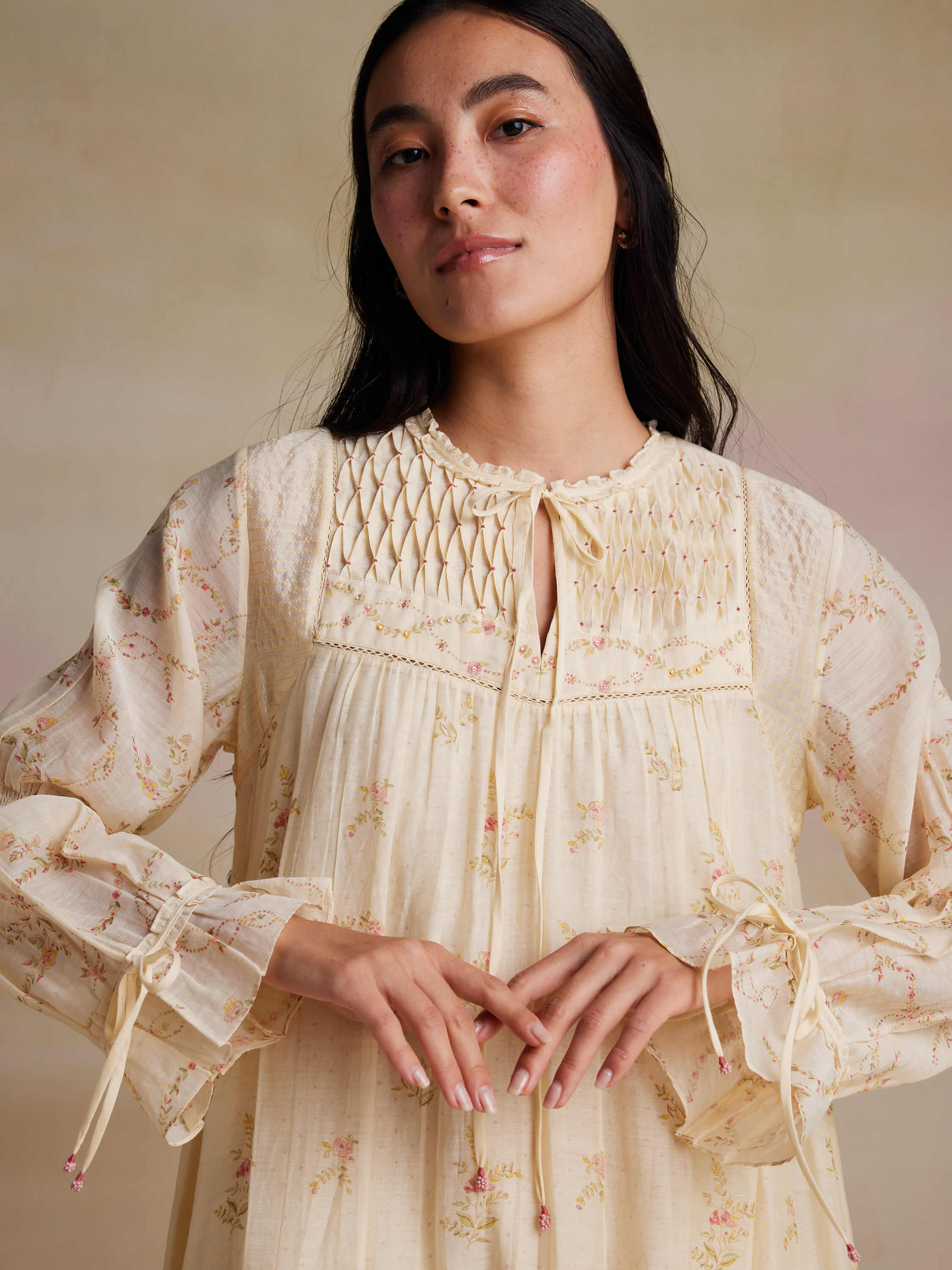 Woman in floral embroidered dress with detailed smocked bodice.