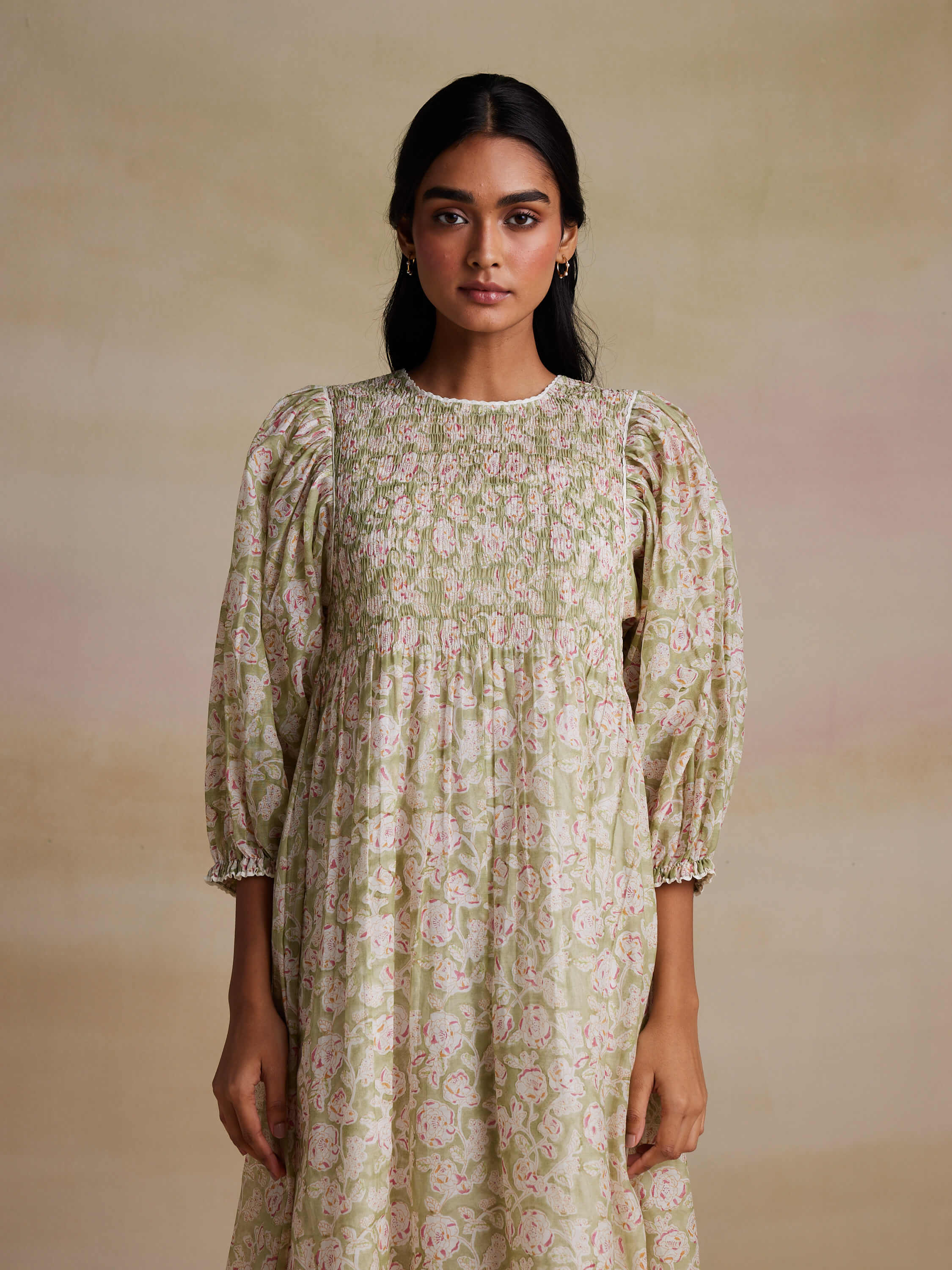 Woman in floral long-sleeve dress against a neutral background.