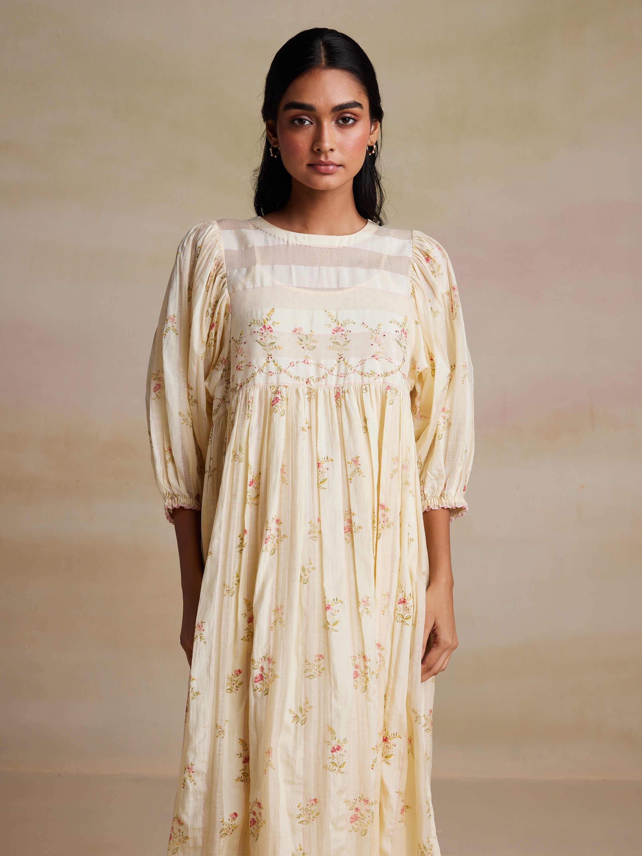 Woman modeling a floral embroidered cream dress with puff sleeves.