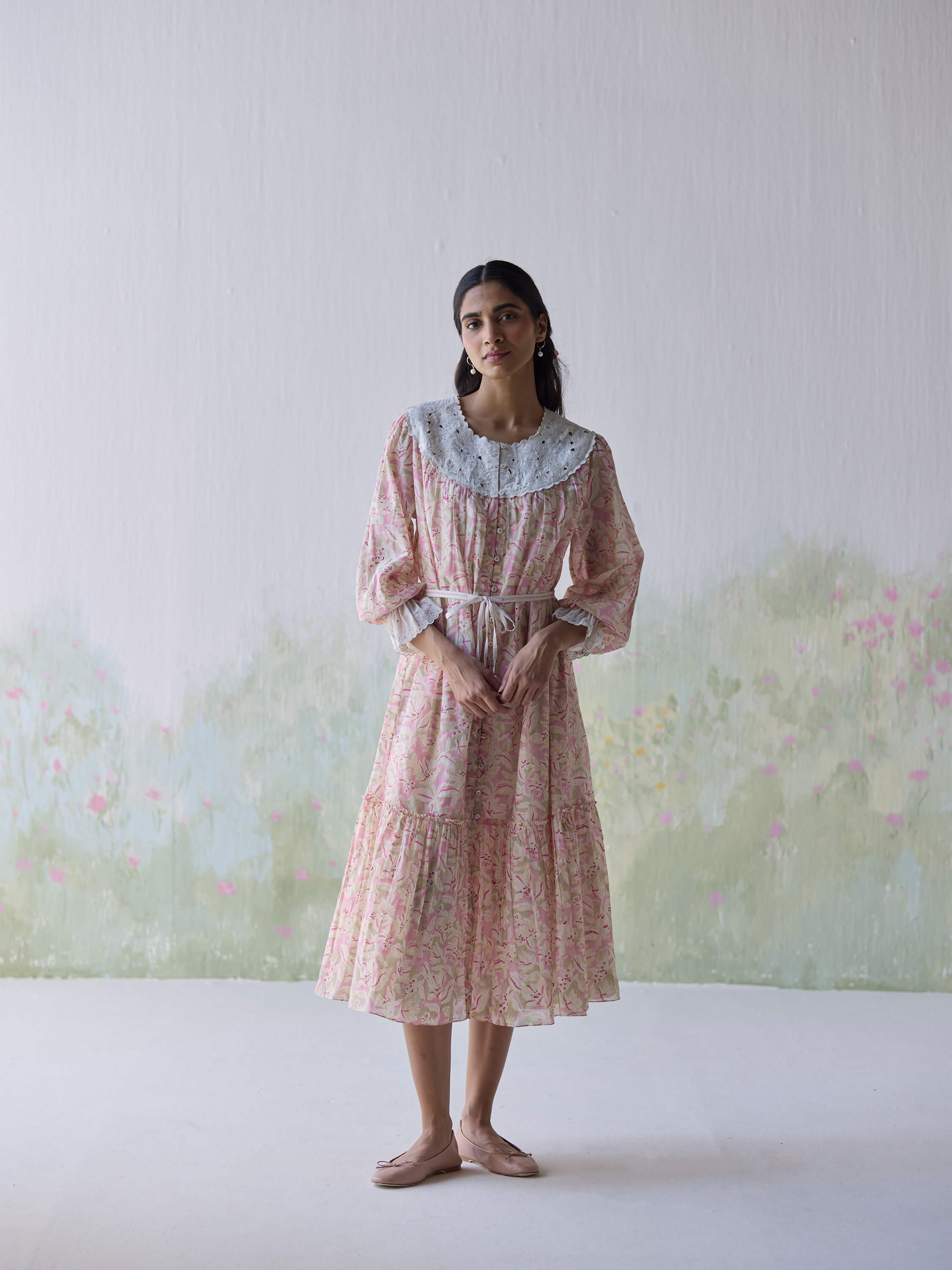 Woman in floral dress standing against a floral background.