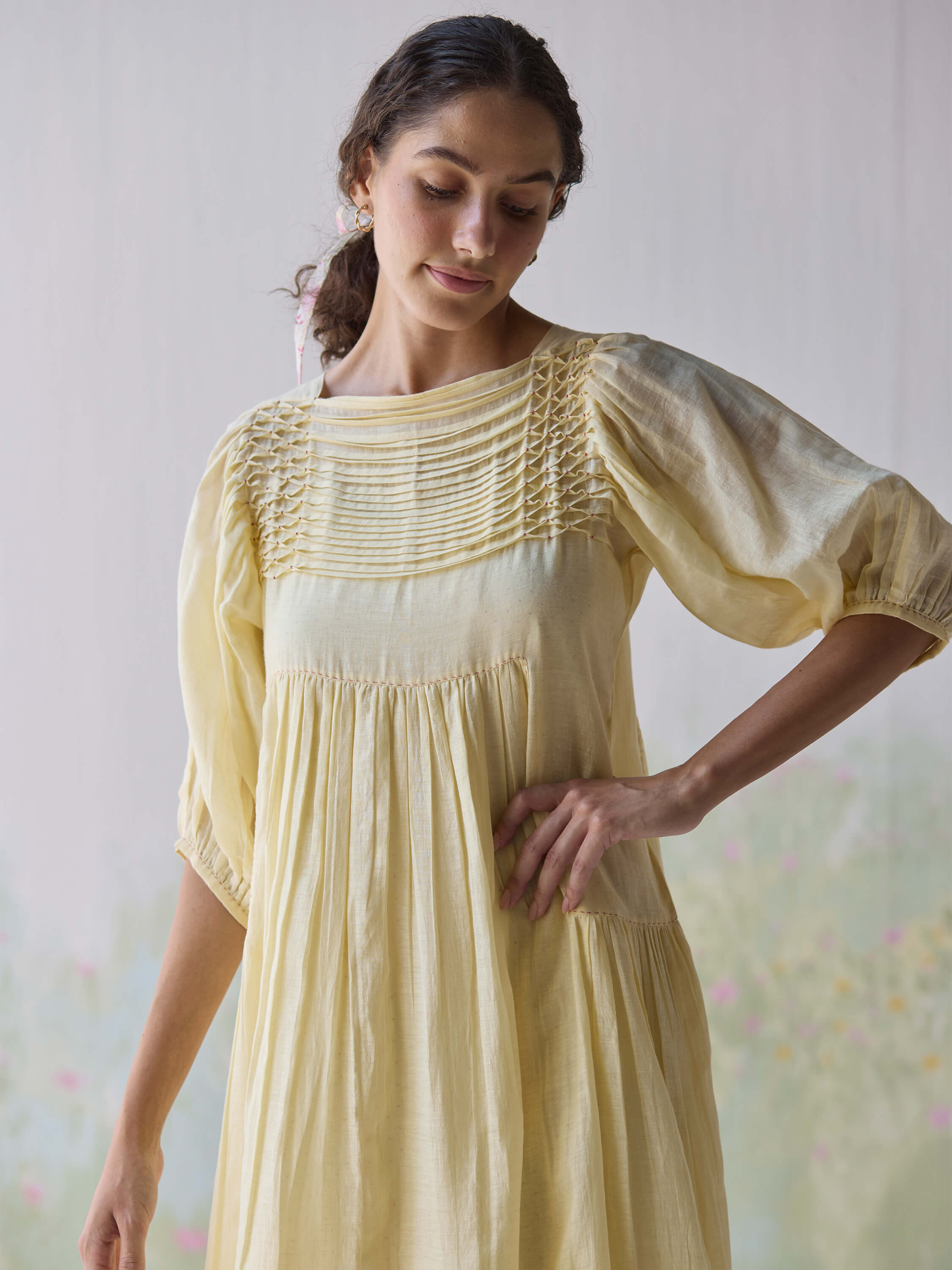 Woman in a light yellow dress with detailed pleating.