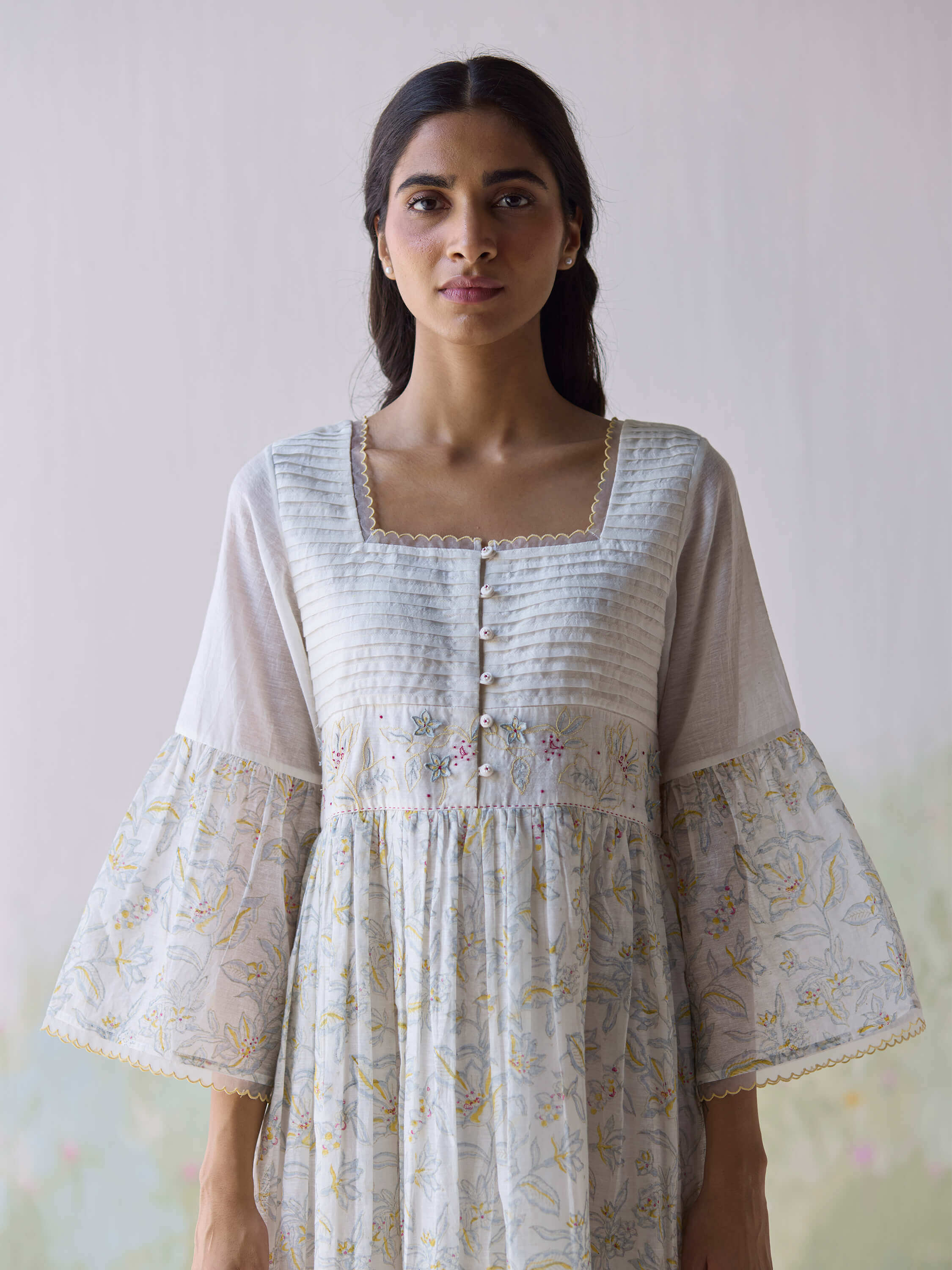 Woman wearing a floral embroidered dress with ruffle details.