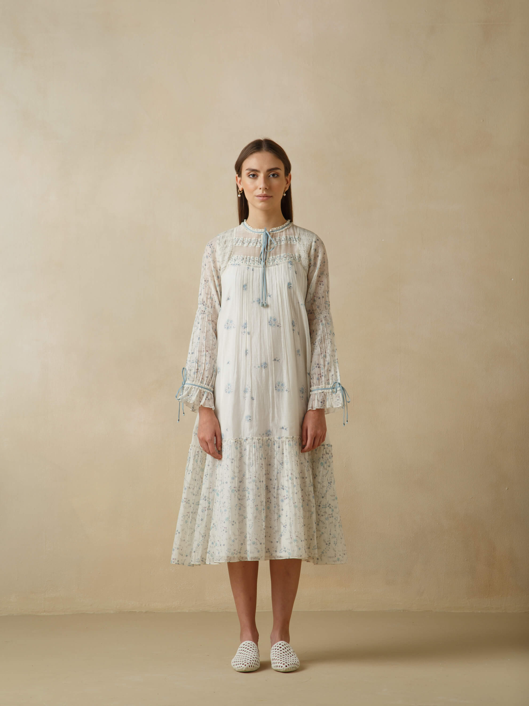 Woman wearing a white floral dress with lace sleeves and white shoes.