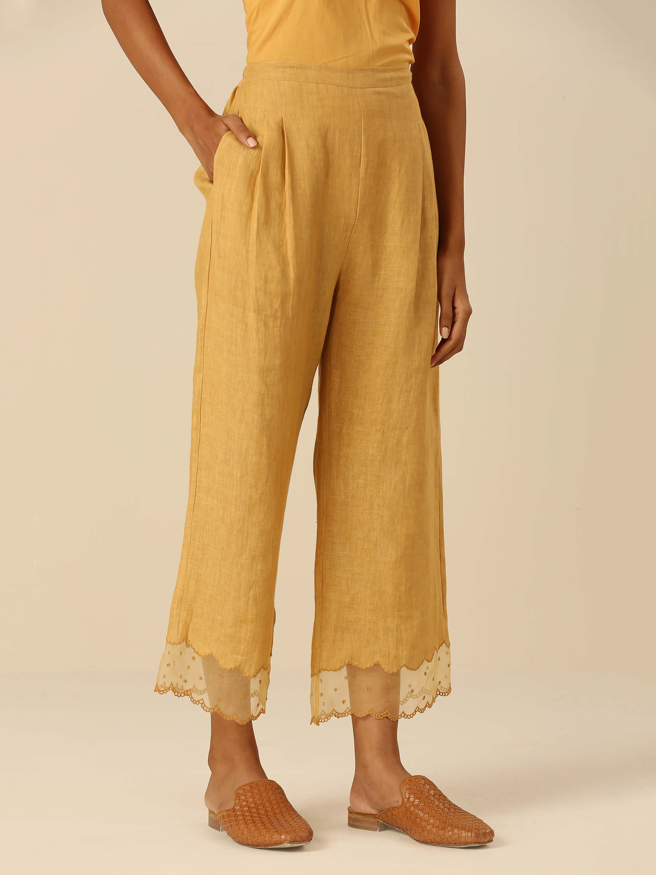 Woman wearing mustard yellow cropped pants with lace hem detailing.