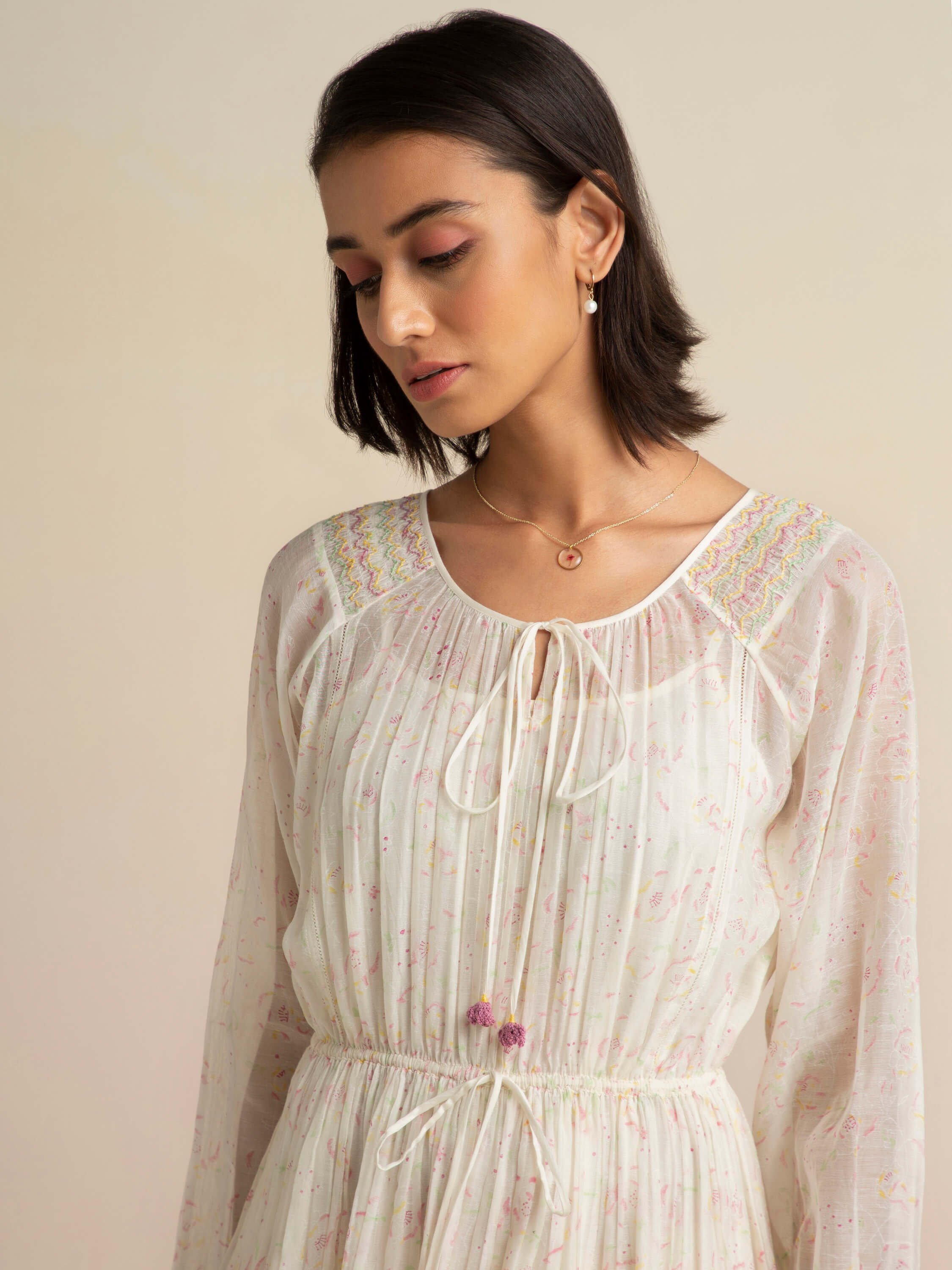 Woman in a white floral dress with a thoughtful expression.