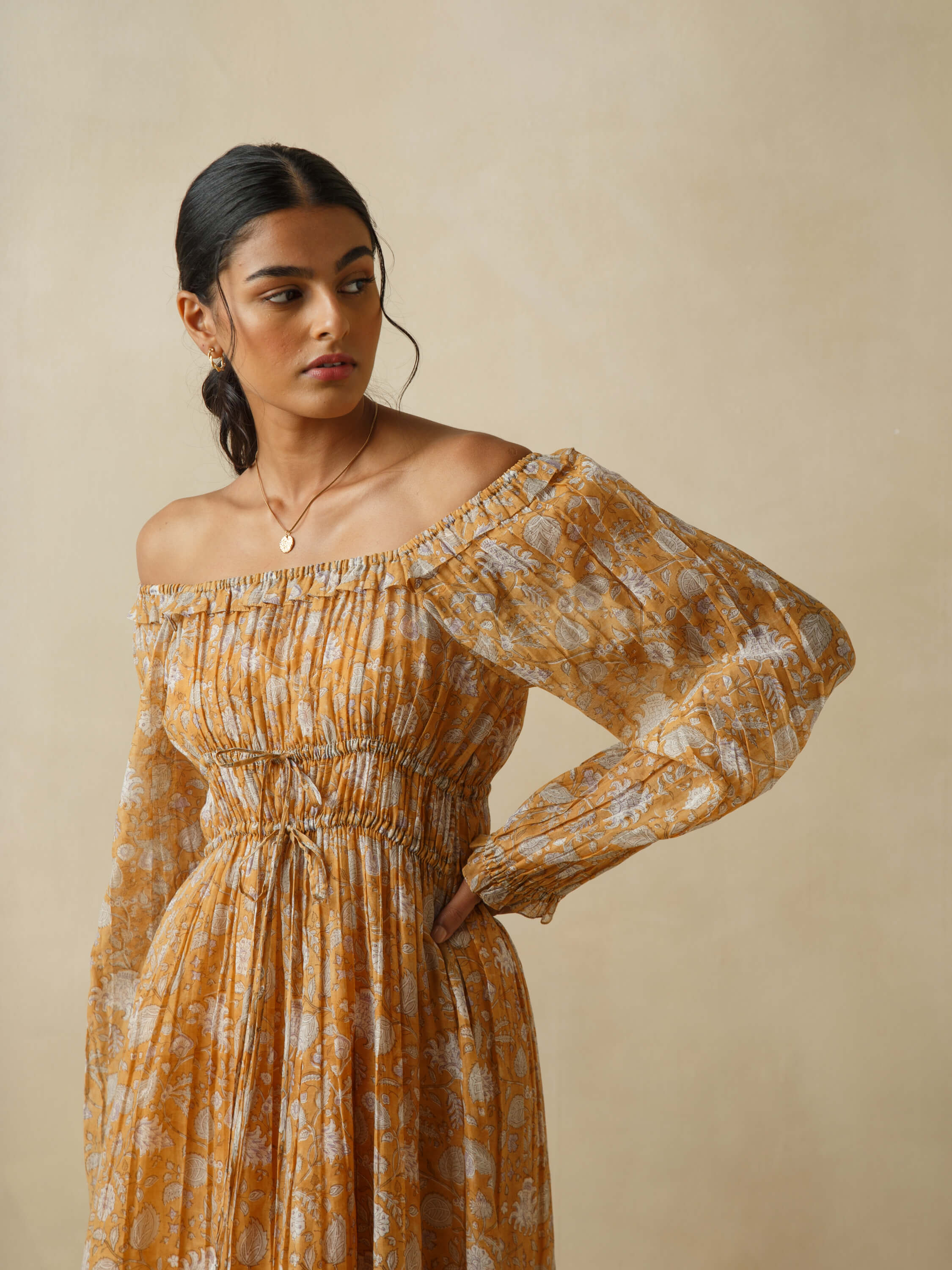Woman wearing an off-shoulder orange floral dress, looking sideways.