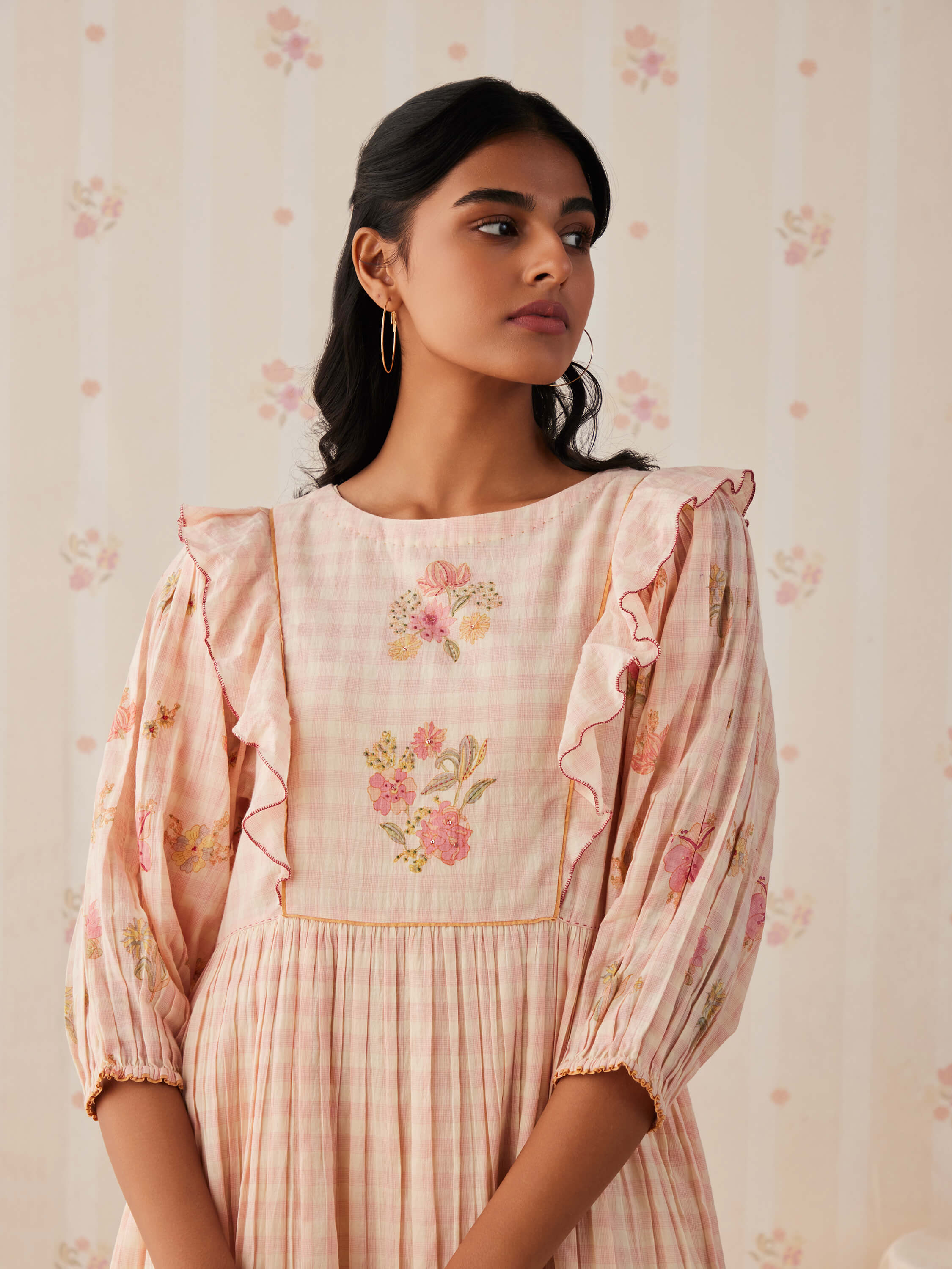 Young woman in floral pastel dress with ruffled sleeves.