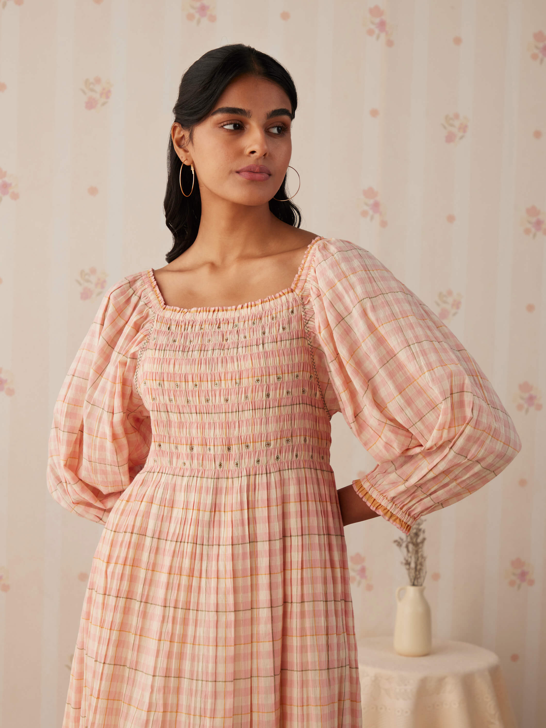 Woman wearing a pink plaid dress with puff sleeves.
