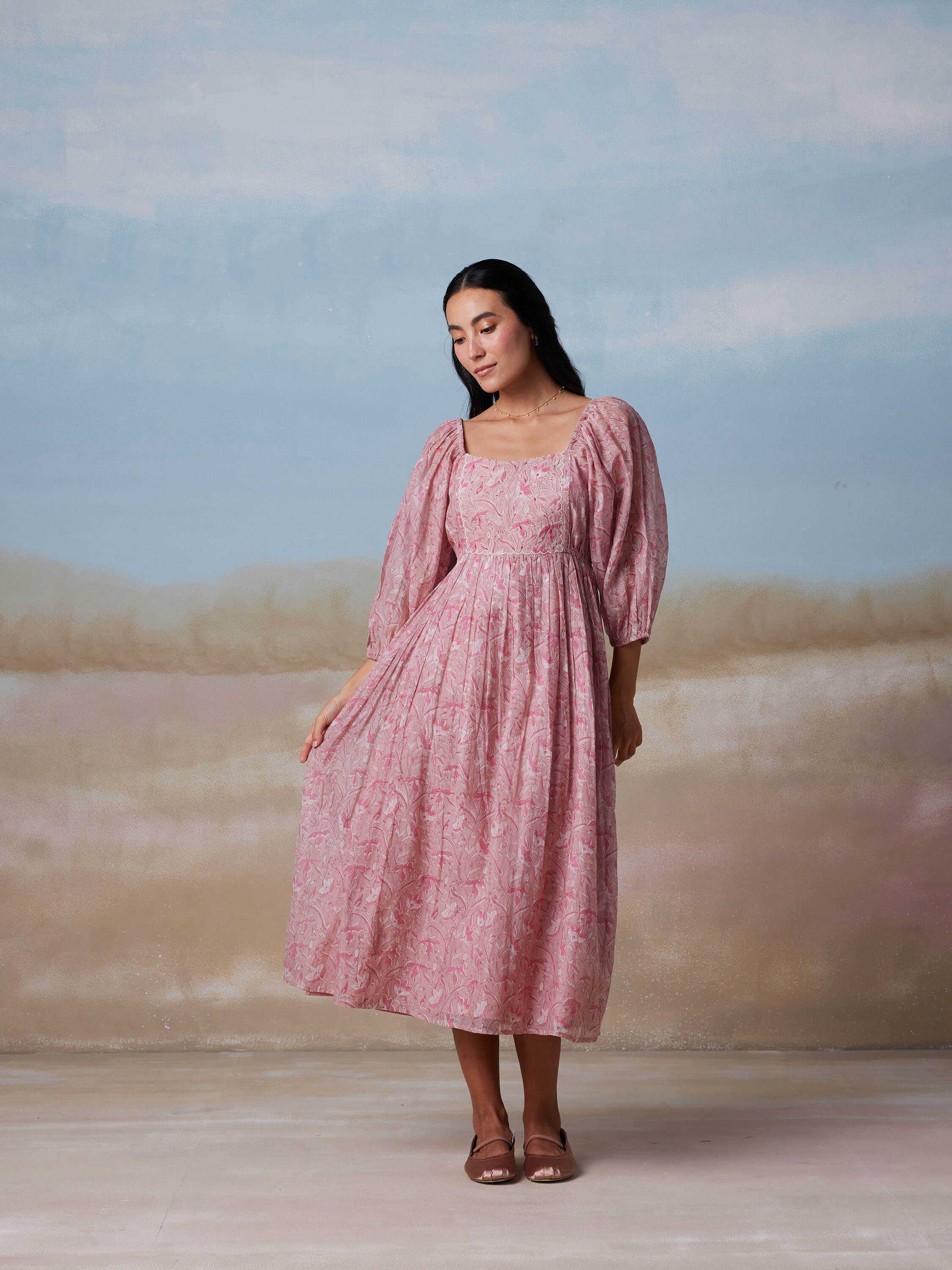 Woman modeling a pink floral dress against a muted background.
