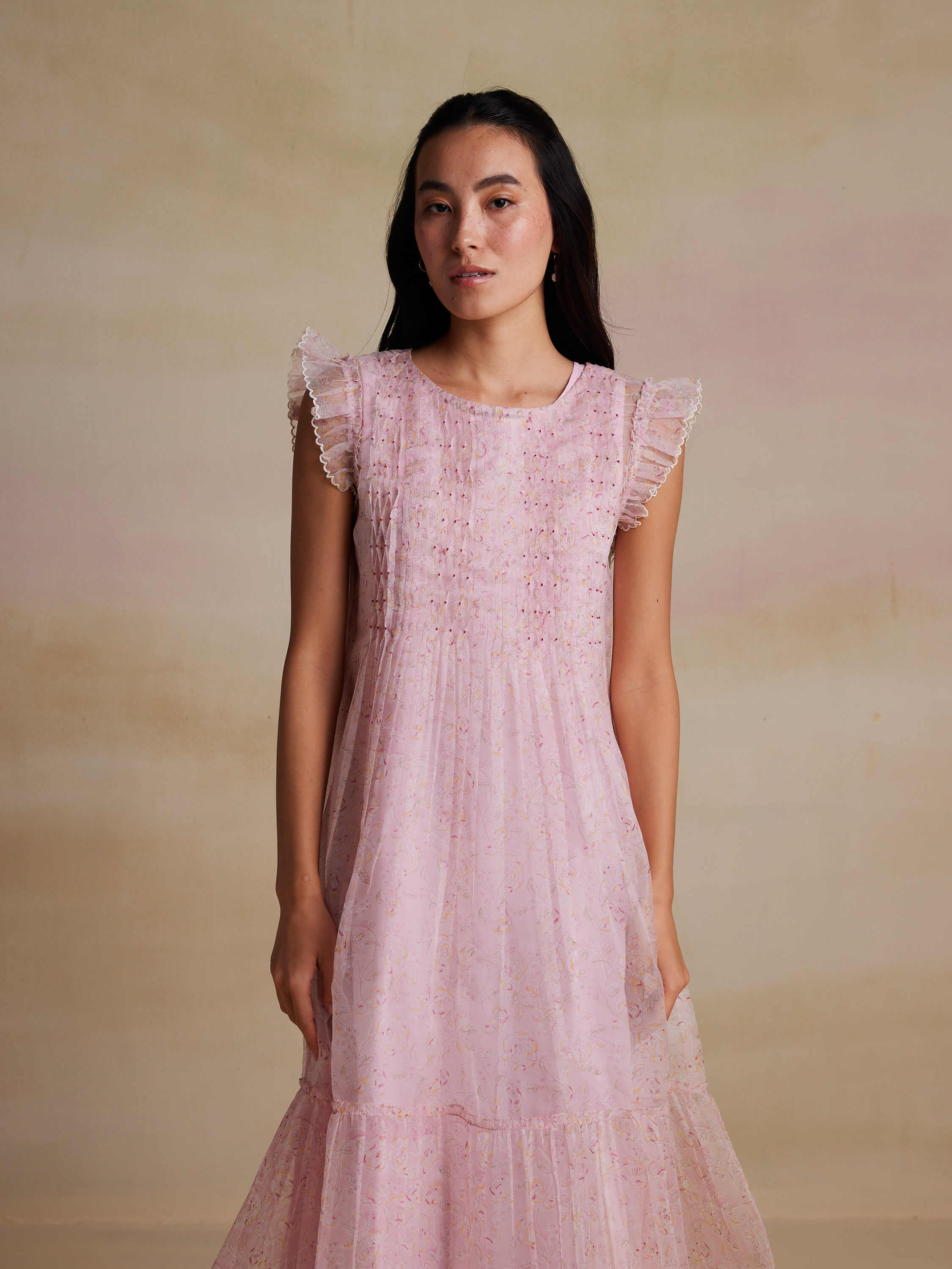 Woman in a pink sleeveless dress with ruffled shoulders.