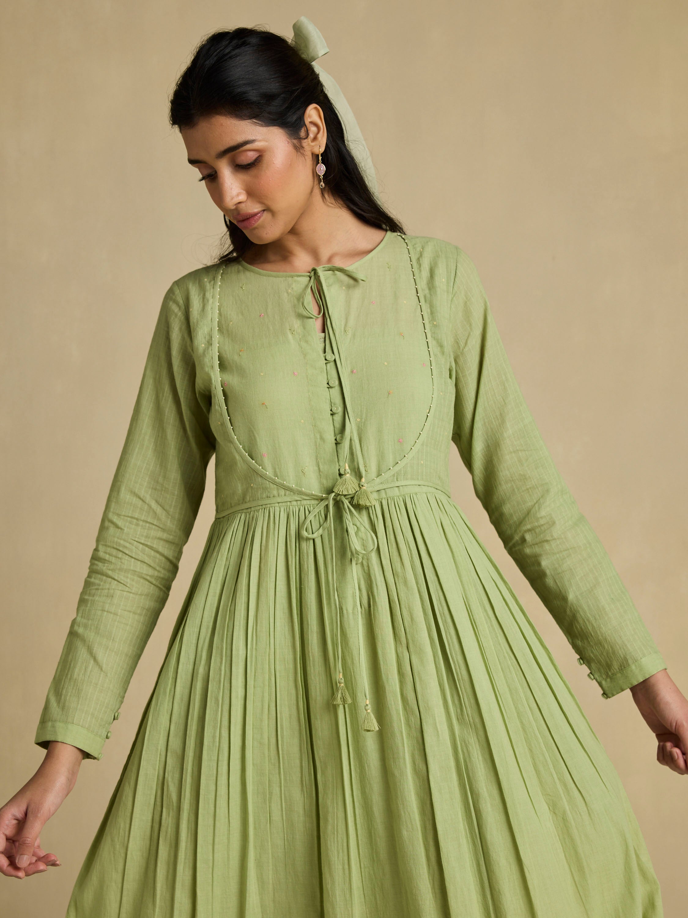 Woman wearing a green dress against a beige background