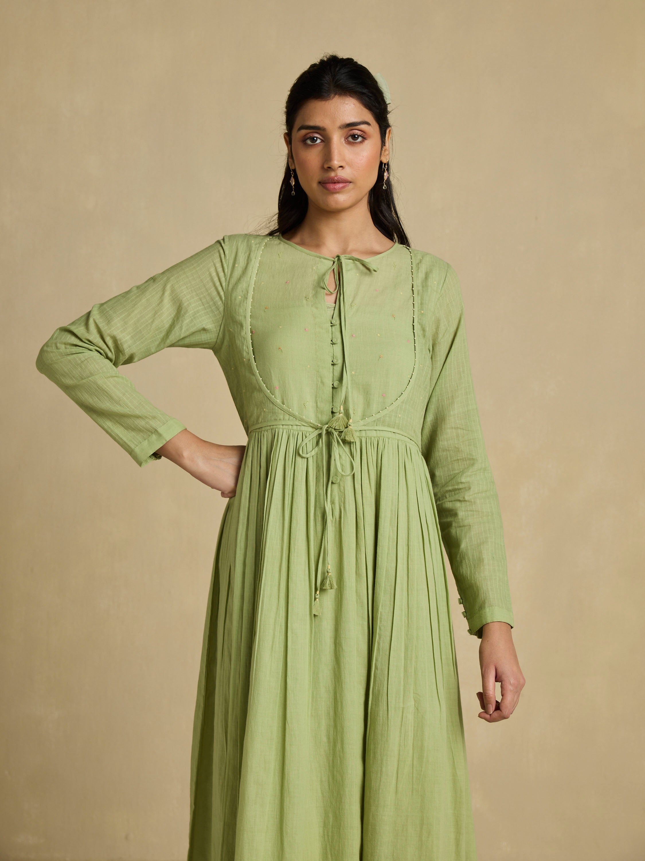 Woman wearing a green dress against a beige background