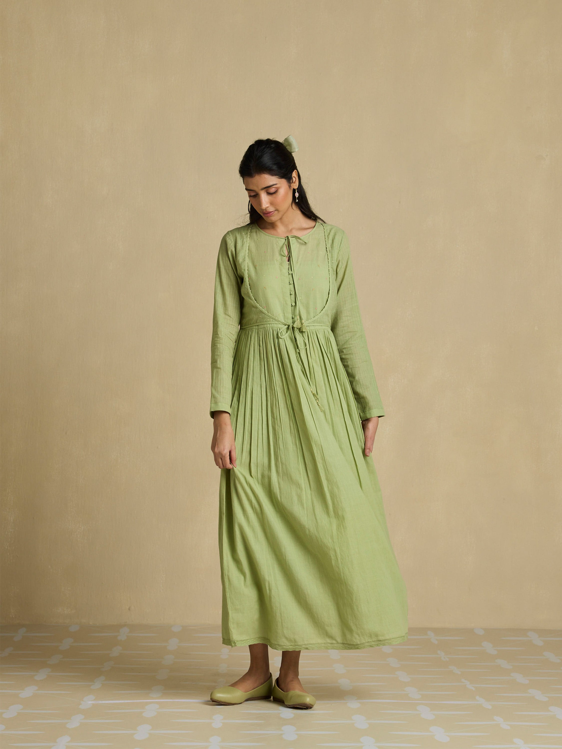 Woman wearing a green dress against a beige background