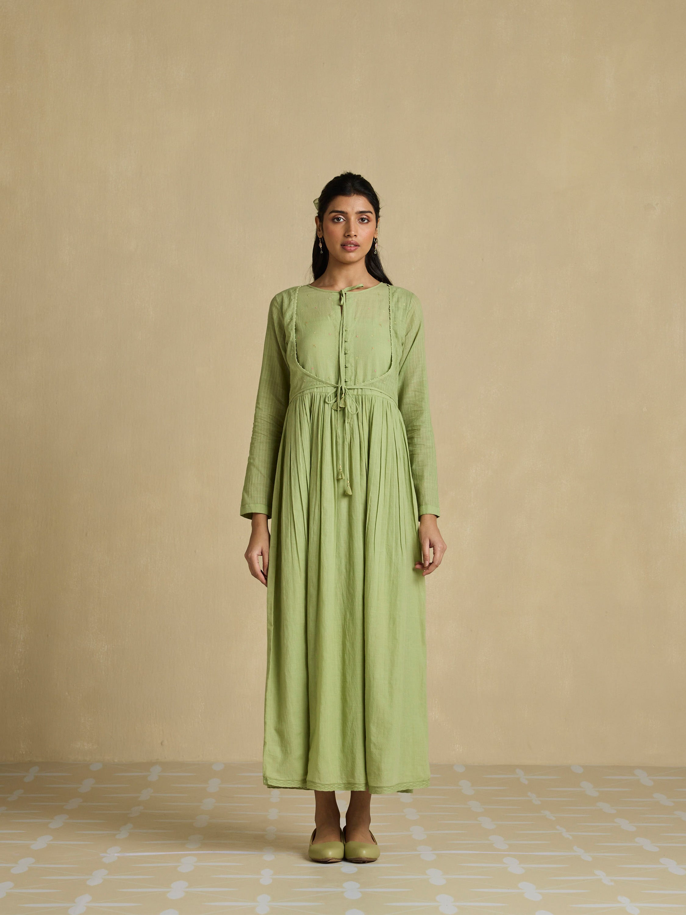 Woman wearing a green dress against a beige background