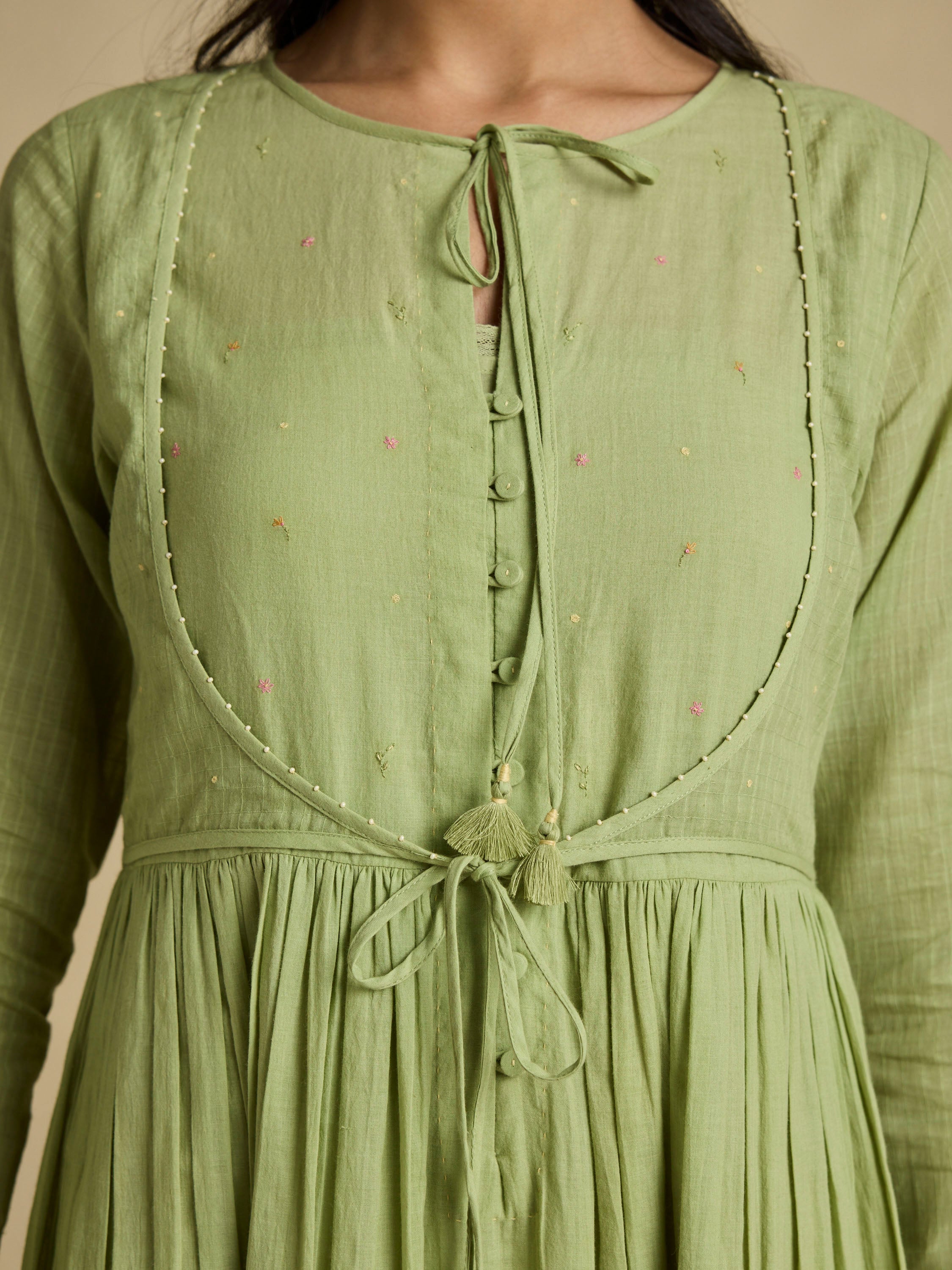 Green dress with intricate detailing on a neutral background