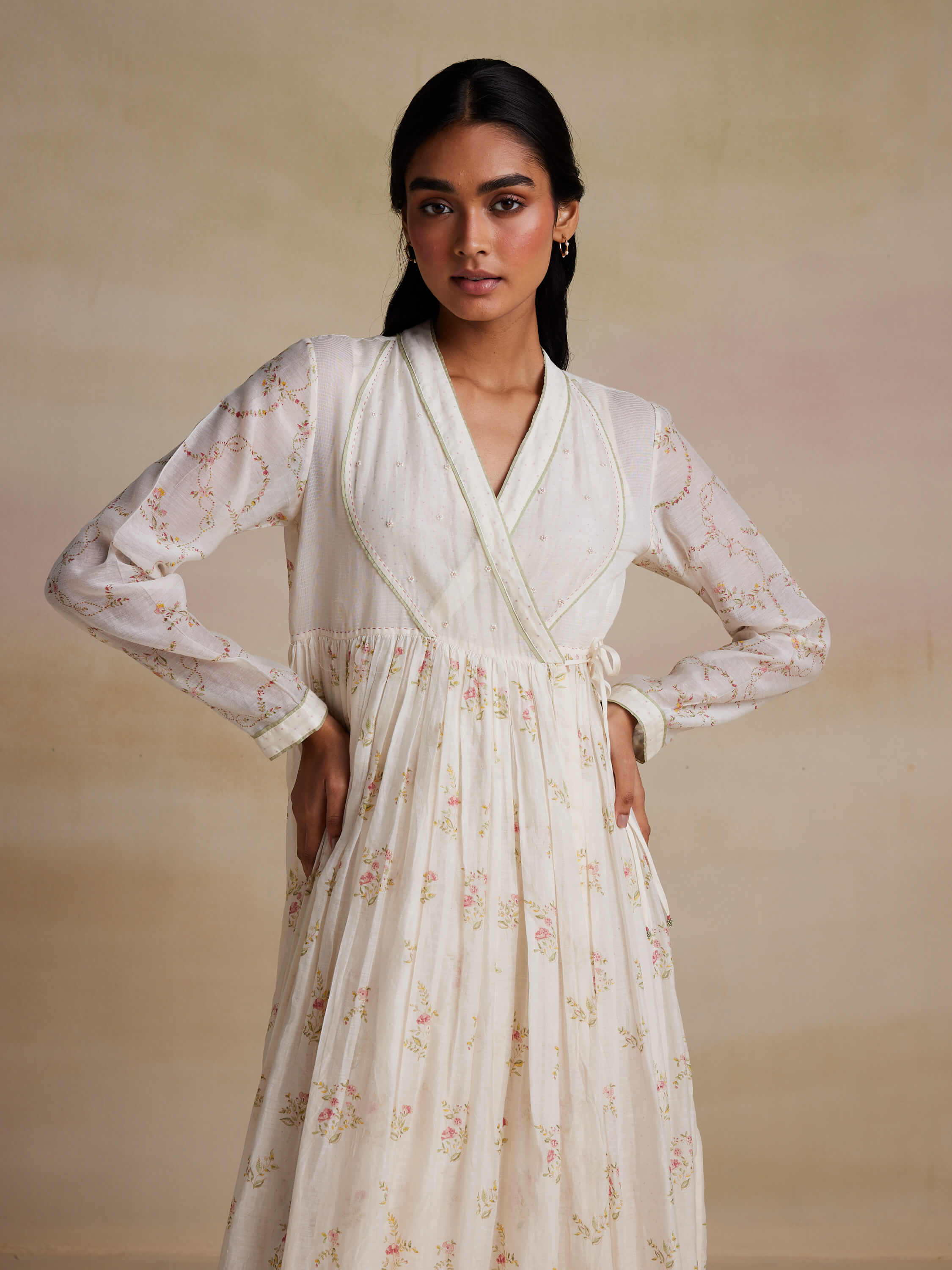 Woman wearing a white floral dress with long sleeves.
