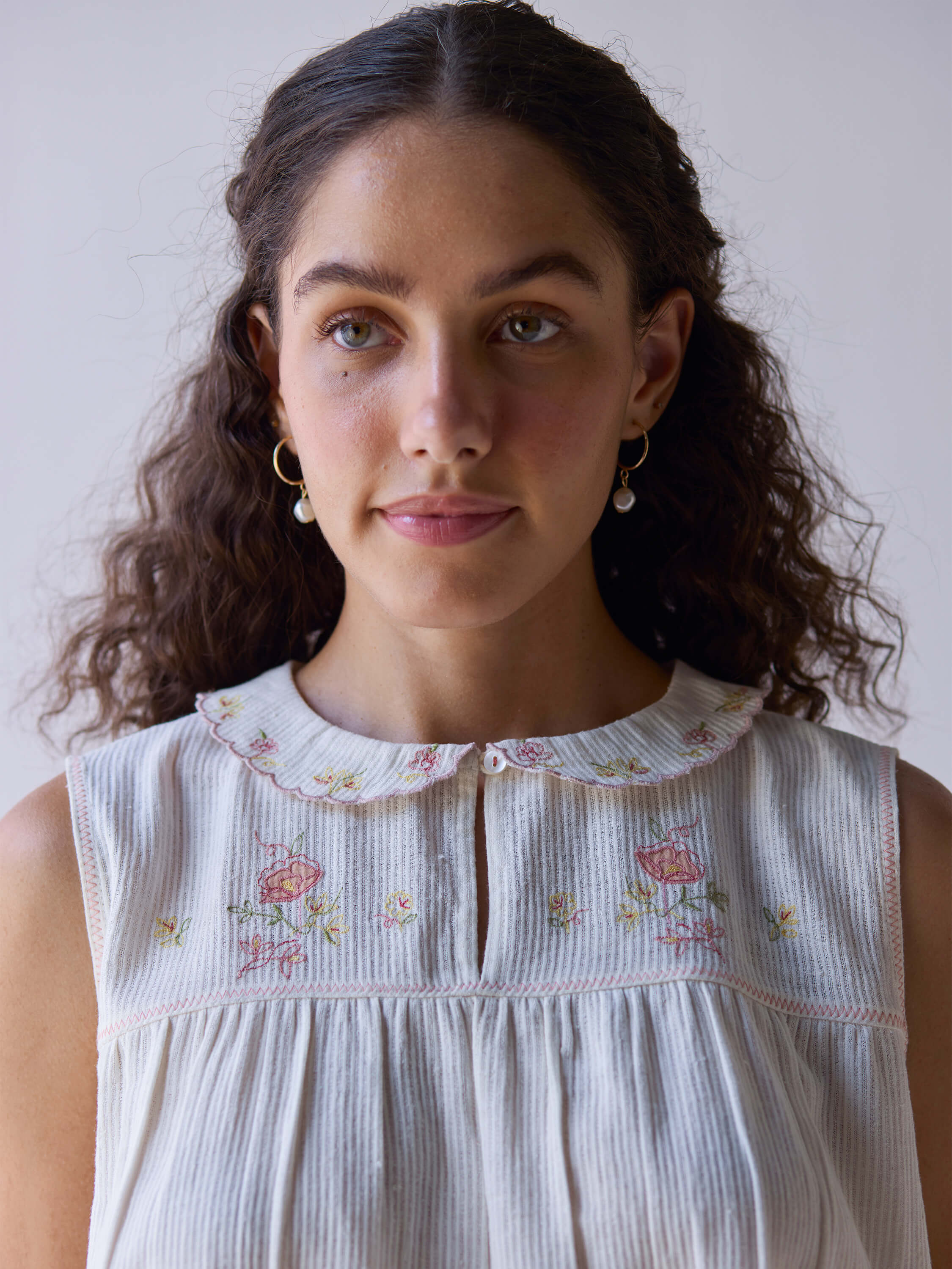 Folk embroidered top with floral design and scalloped collar.