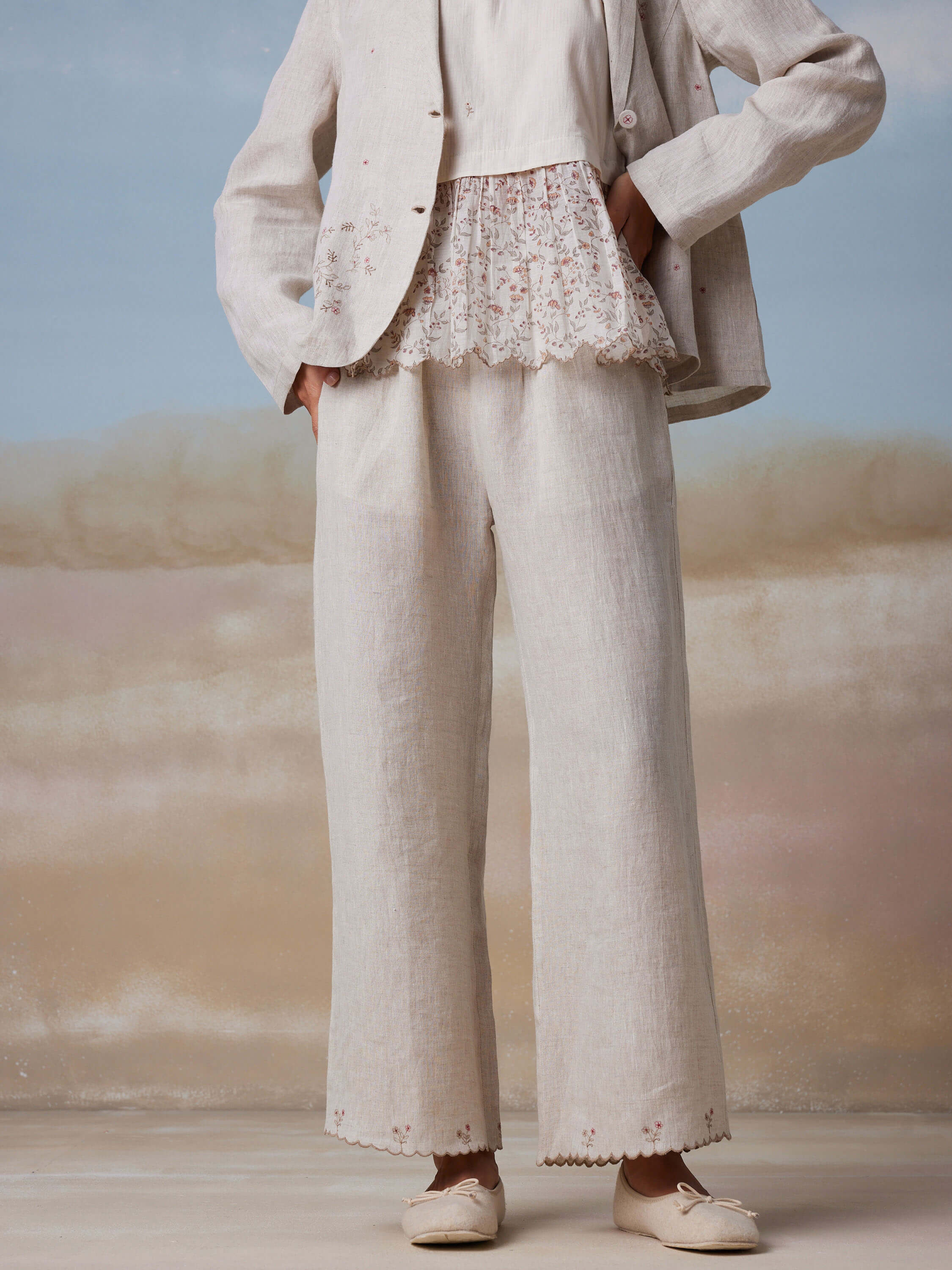 Woman wearing white embroidered linen suit with lace top and flats.