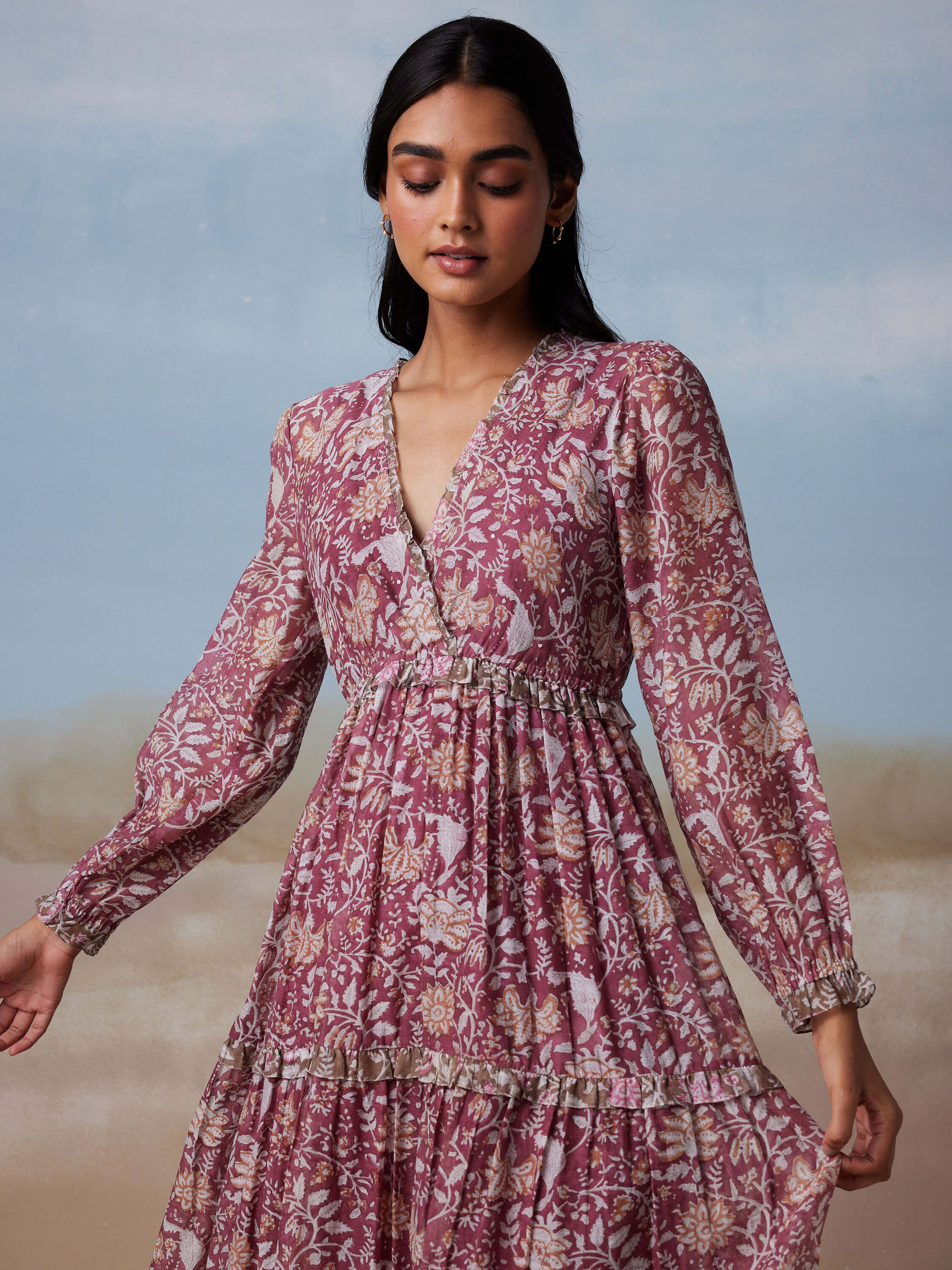 Woman in a floral print long-sleeve dress against pastel background.