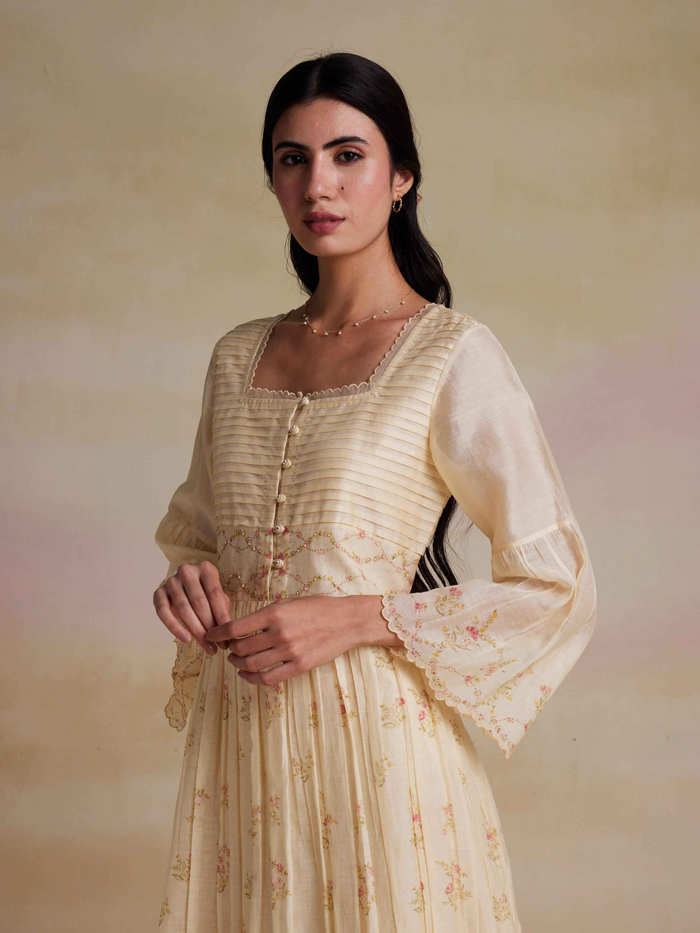 Woman wearing a cream floral long-sleeve dress with elegant embroidery.
