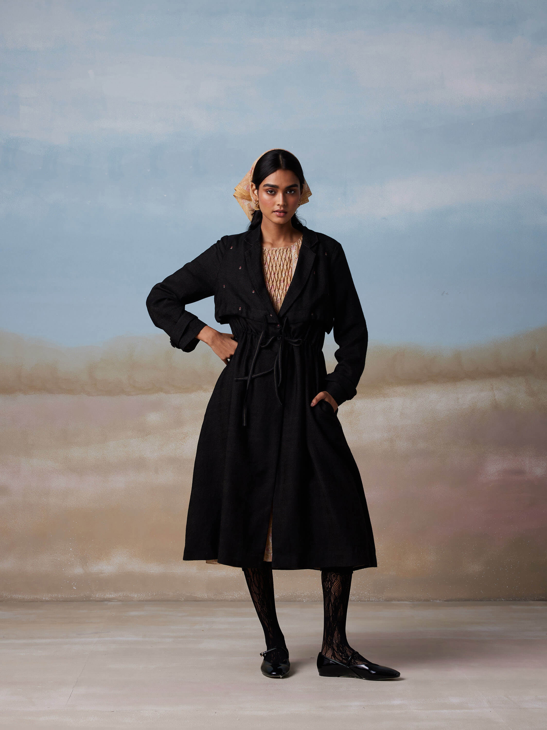 Woman wearing stylish black coat with lace tights and matching flats.