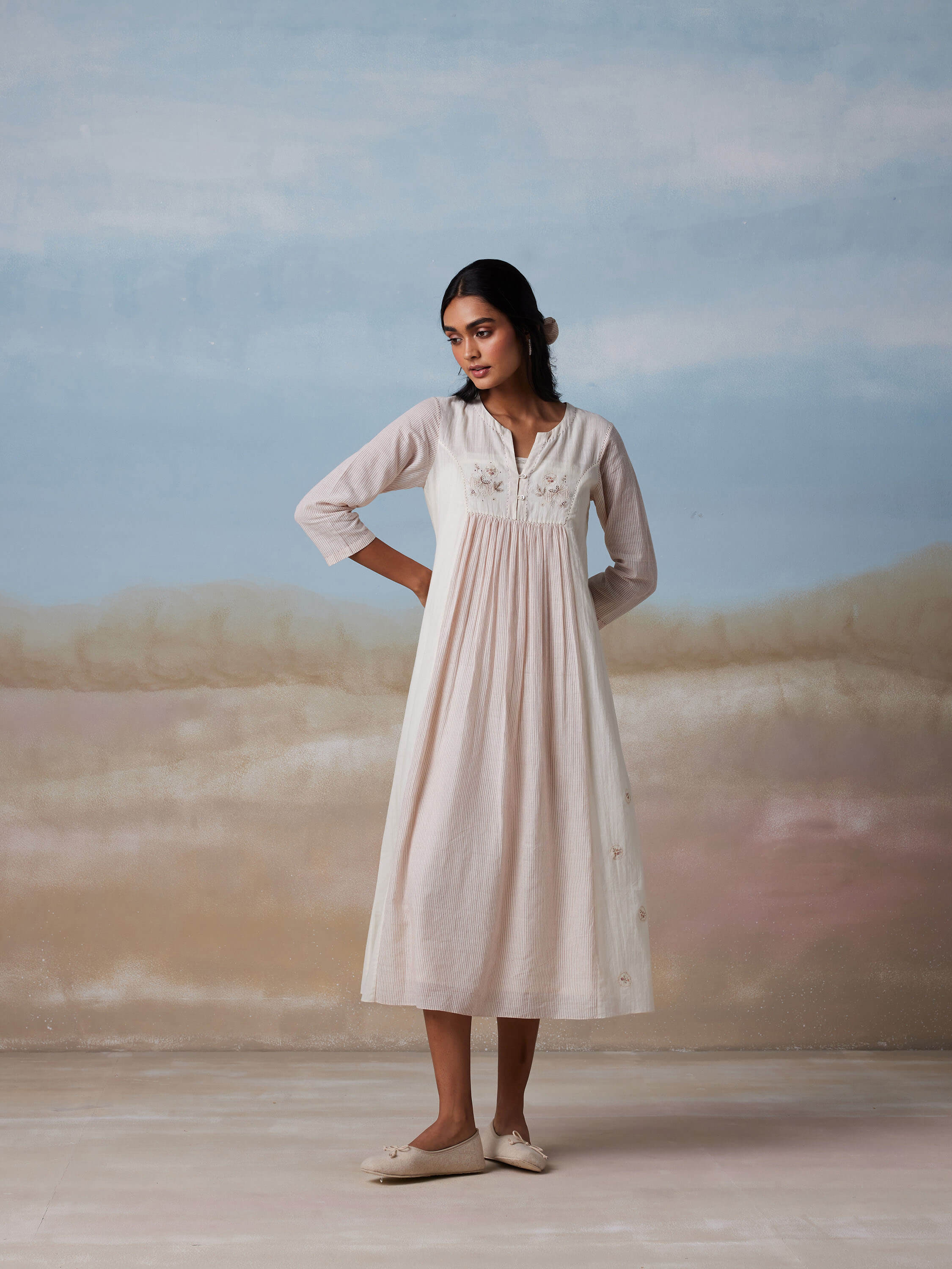Woman wearing a white ankle-length dress in a serene background.
