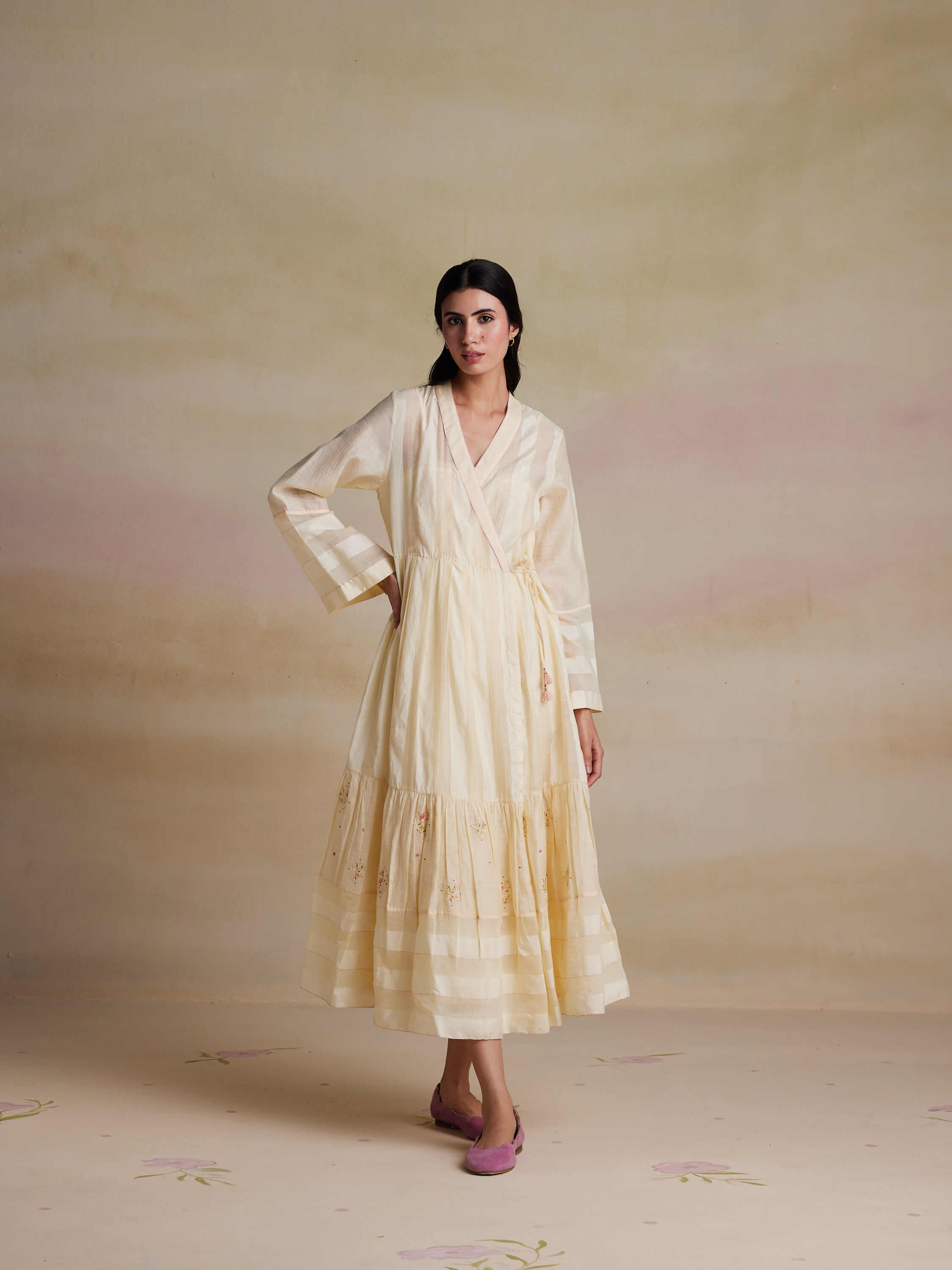 Woman in elegant cream dress posing in studio setting.