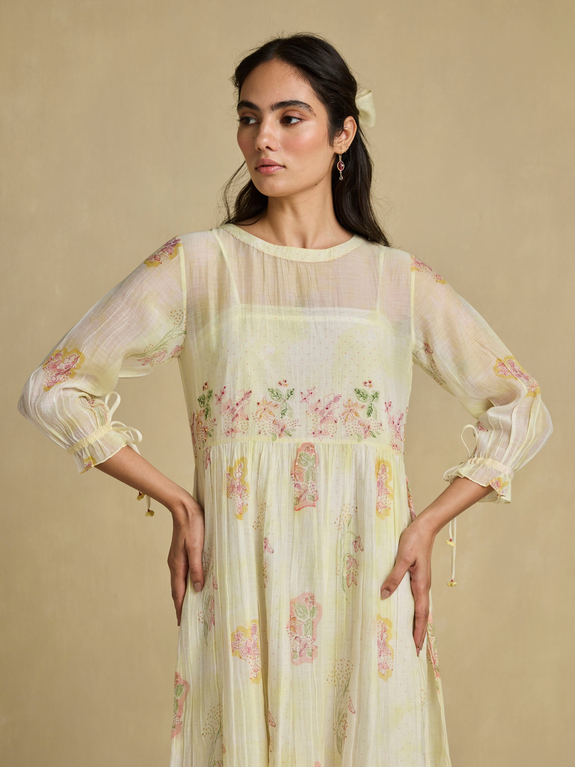 Woman wearing a light yellow floral dress against a beige background