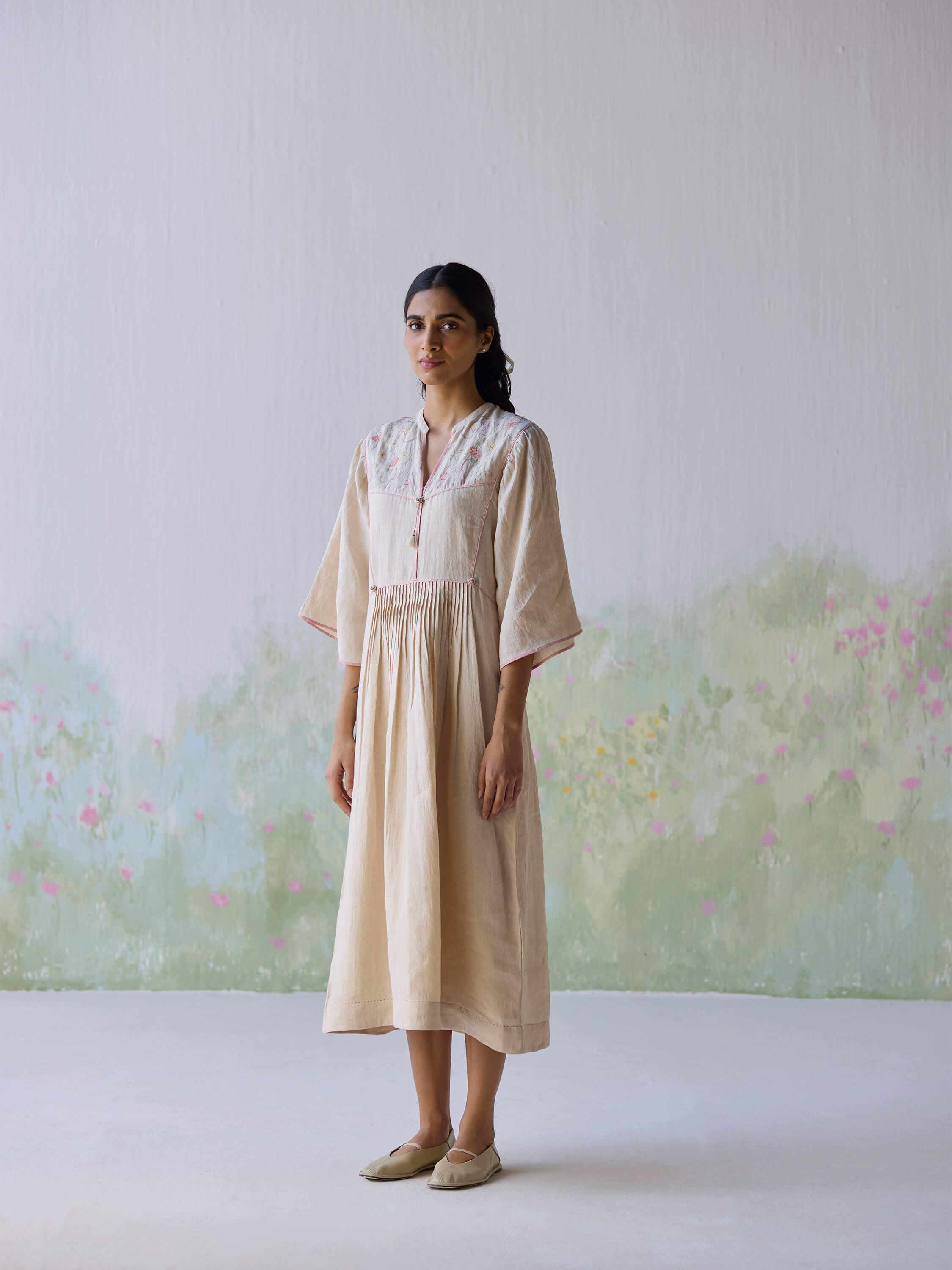Sweetly embroidered kaftan dress model against a floral backdrop.