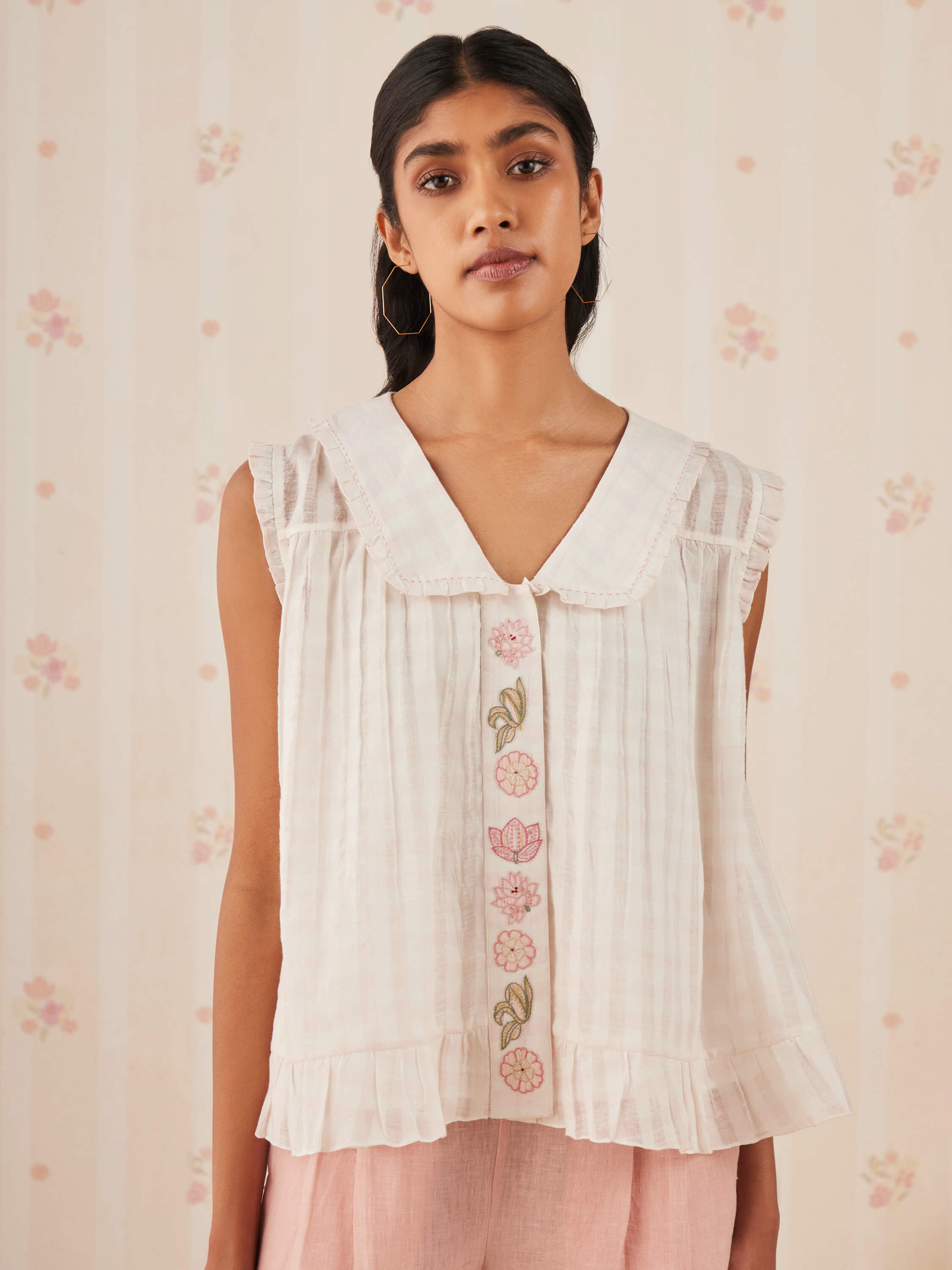 Woman wearing a sleeveless top with floral embroidery details.
