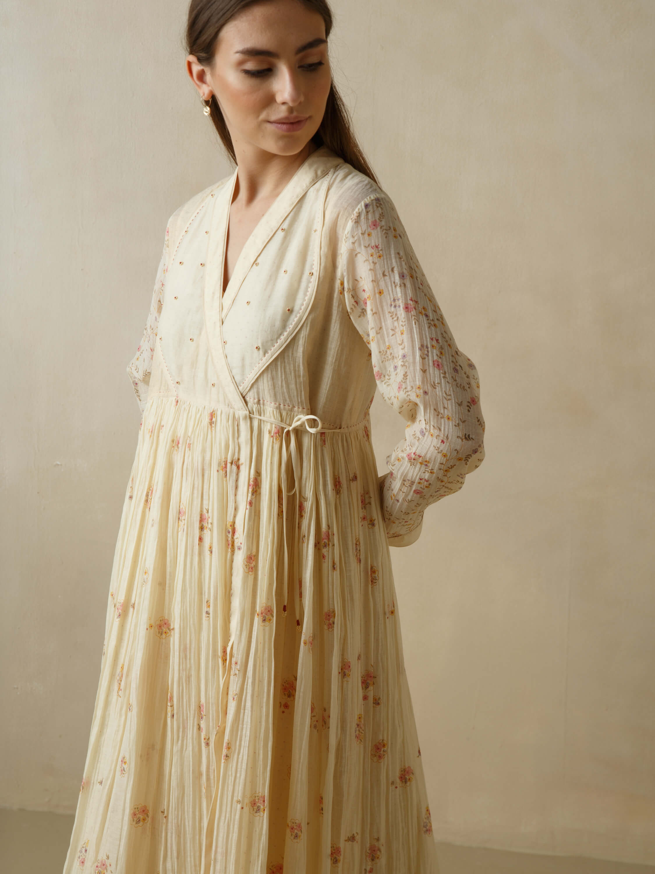 Woman wearing a cream floral dress with delicate embroidery.
