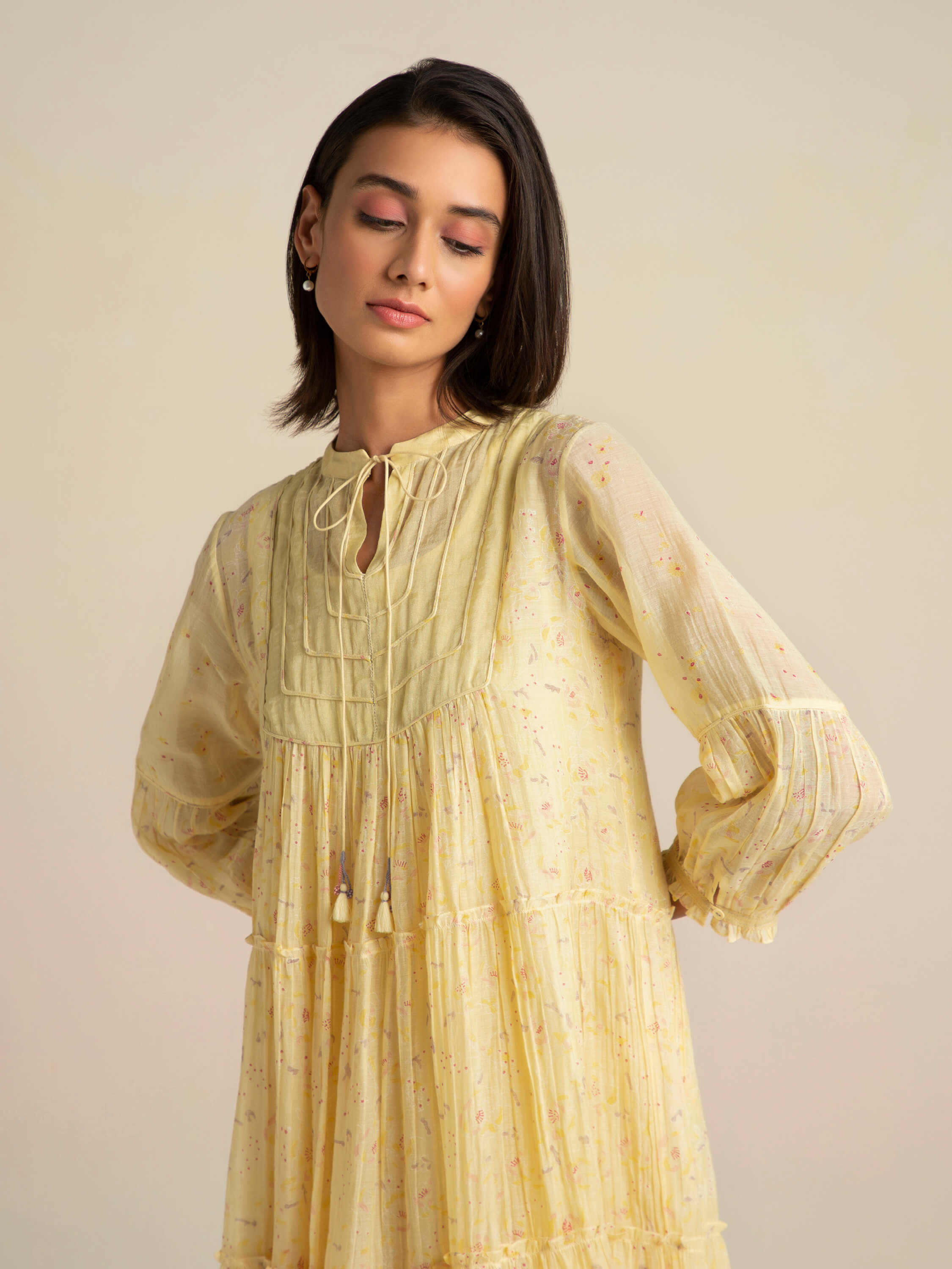 Woman wearing a light-yellow, long sleeve dress with floral design.