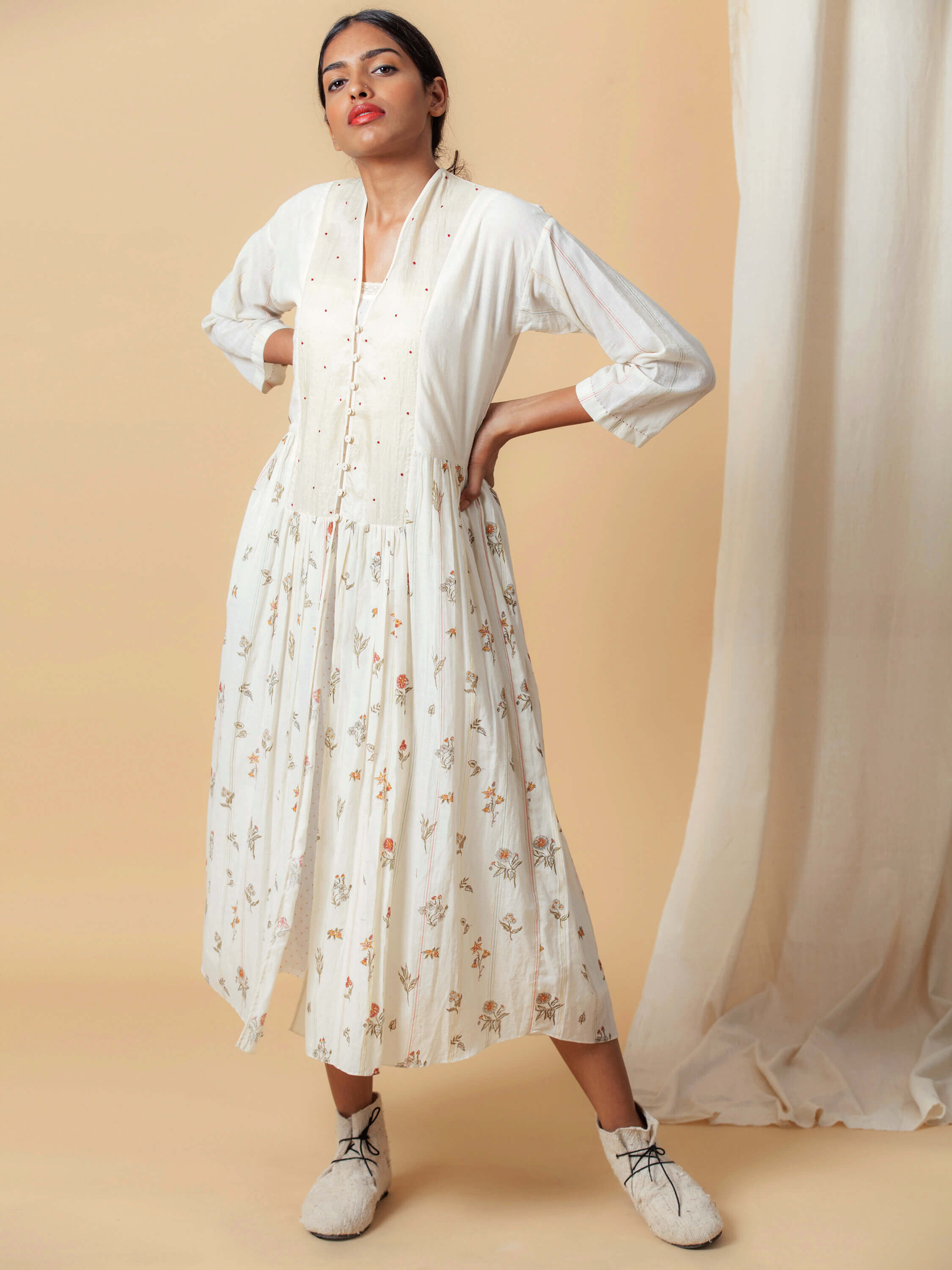 Woman wearing white floral dress posing with neutral background