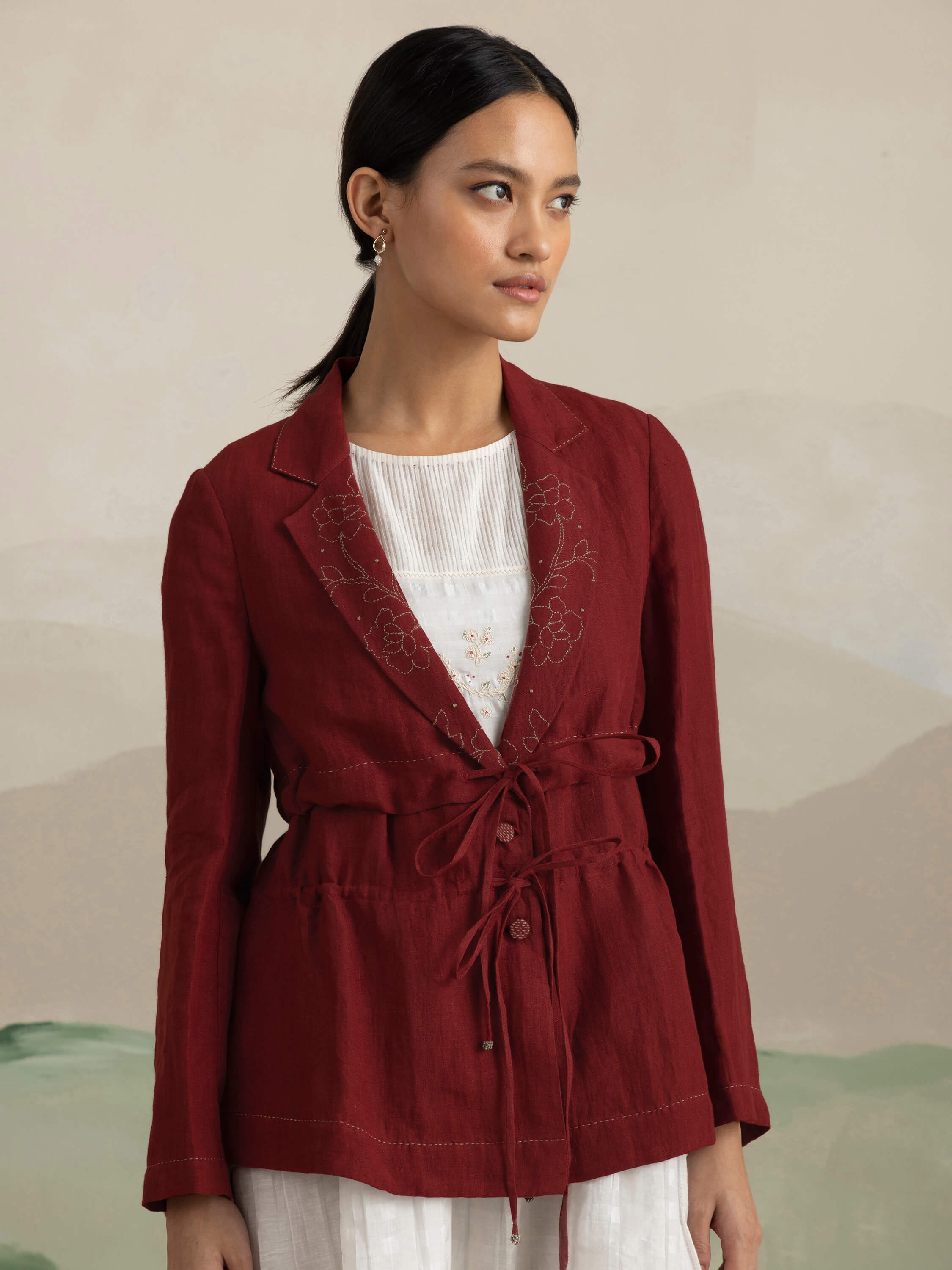 Woman wearing a red jacket with floral embroidery and white top.
