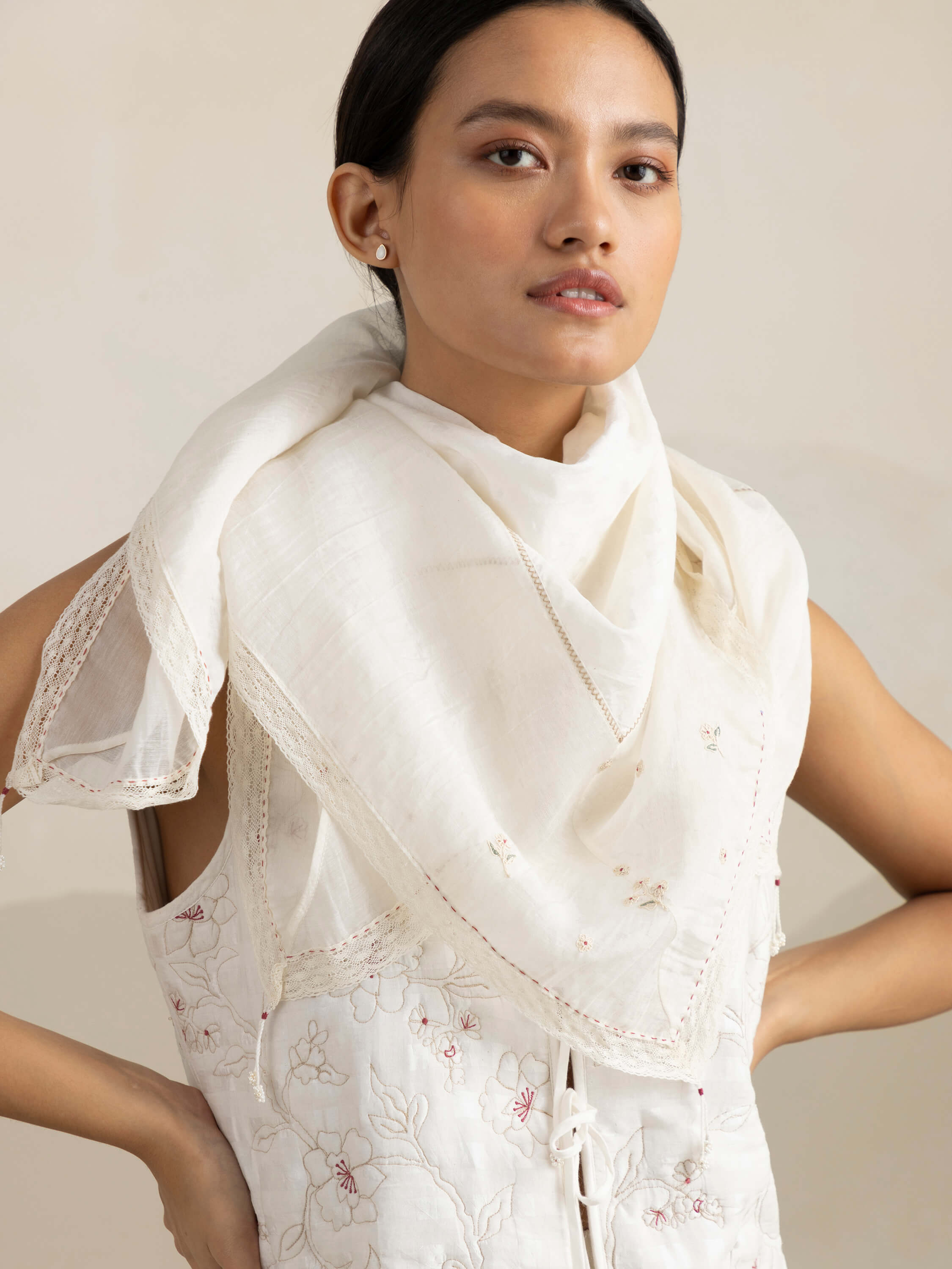 Woman in elegant white embroidered dress and shawl.
