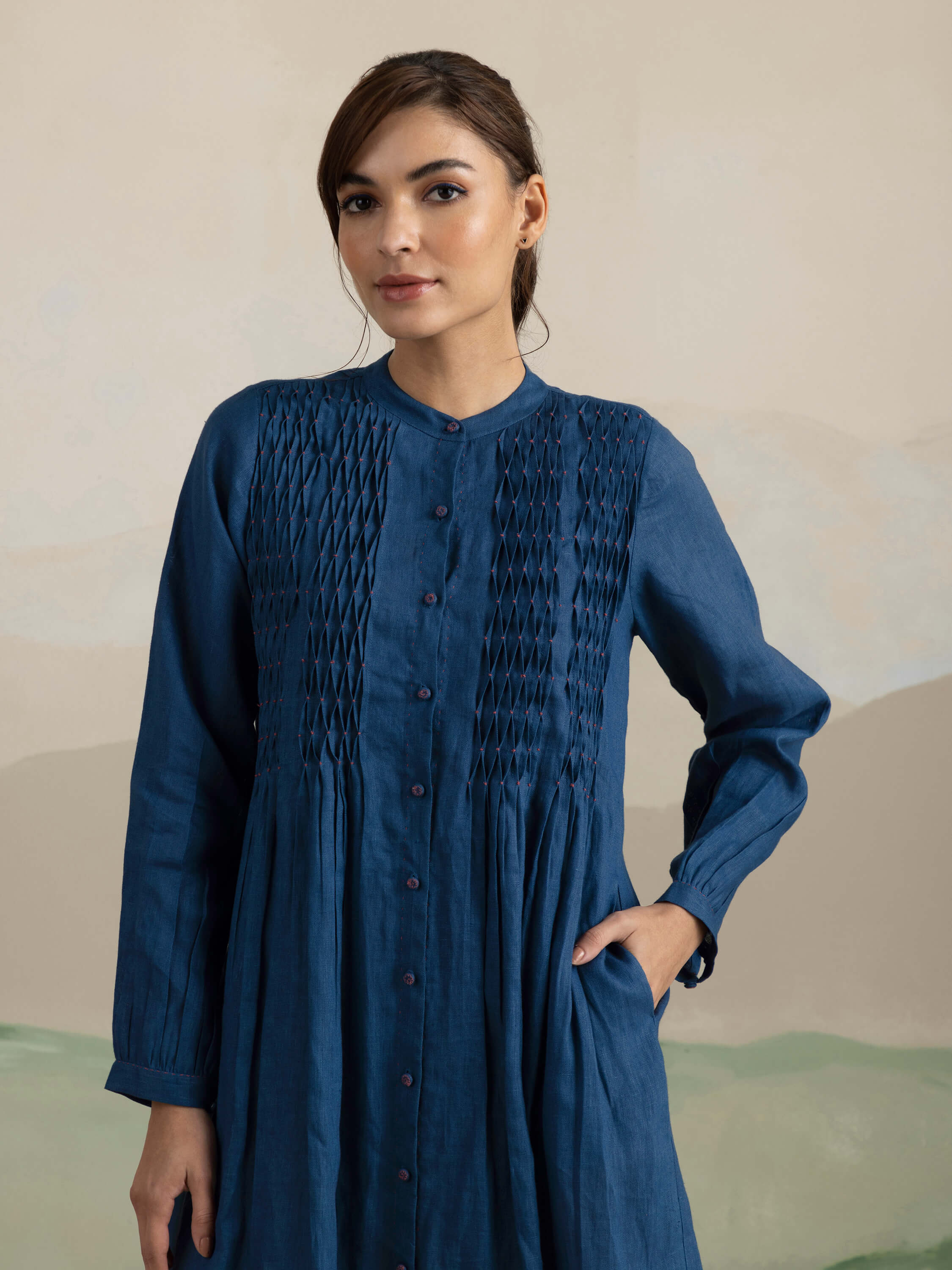 Woman wearing a blue, long-sleeve, button-down dress with a smocked front.