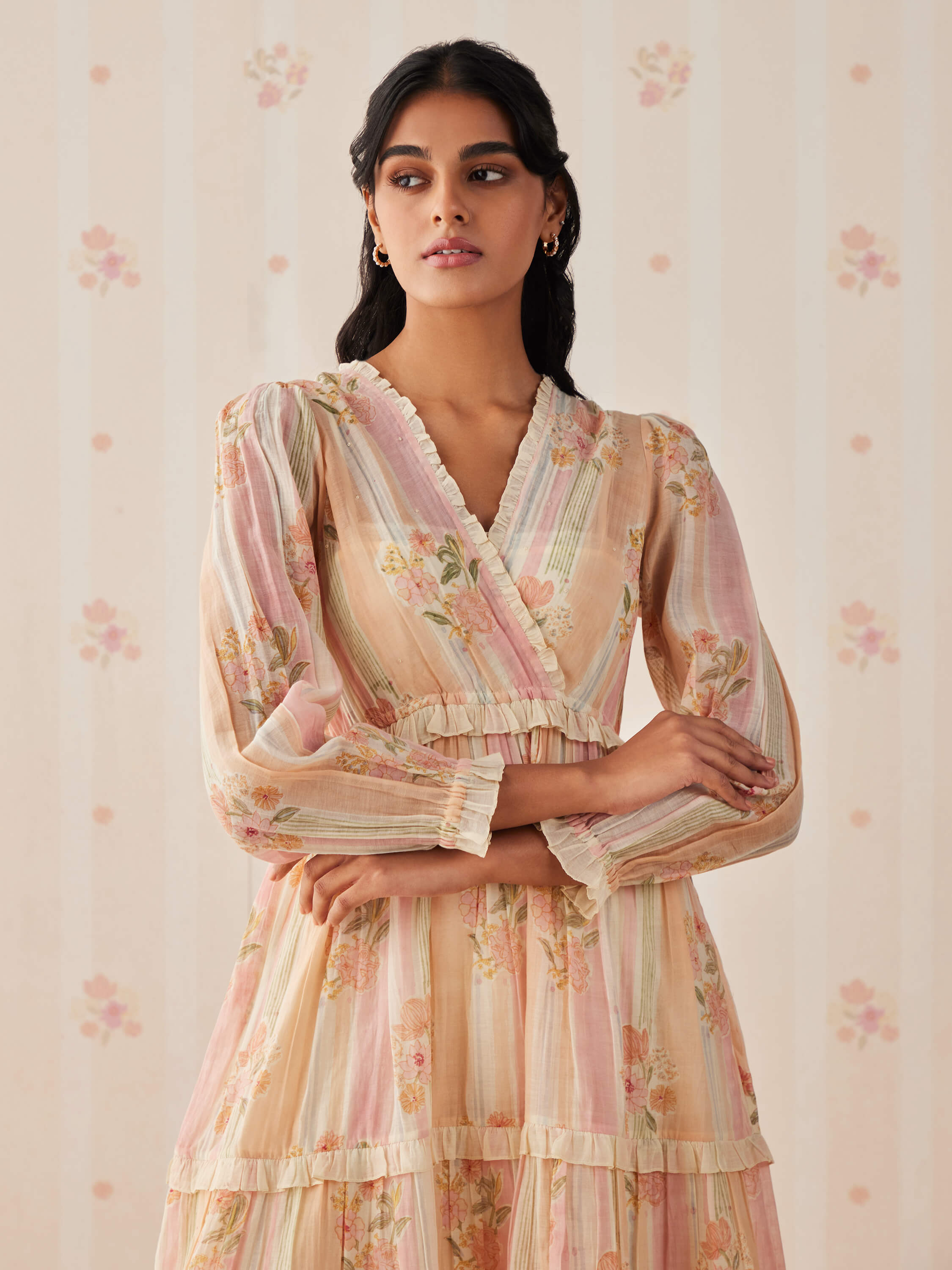 Woman wearing a floral long-sleeve dress with a soft gaze.